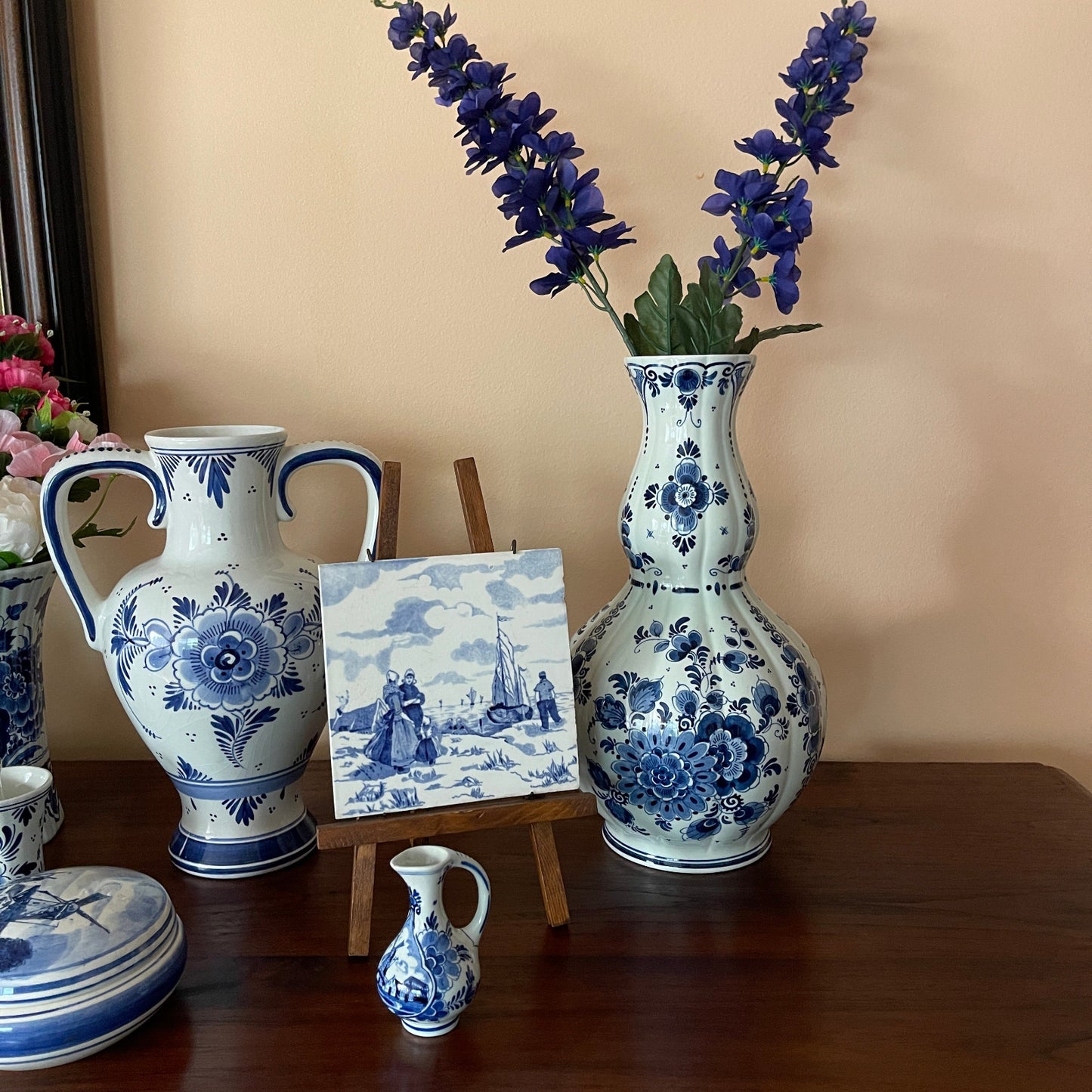 Collection of blue and white ceramic vases and a small painting on a wooden surface.