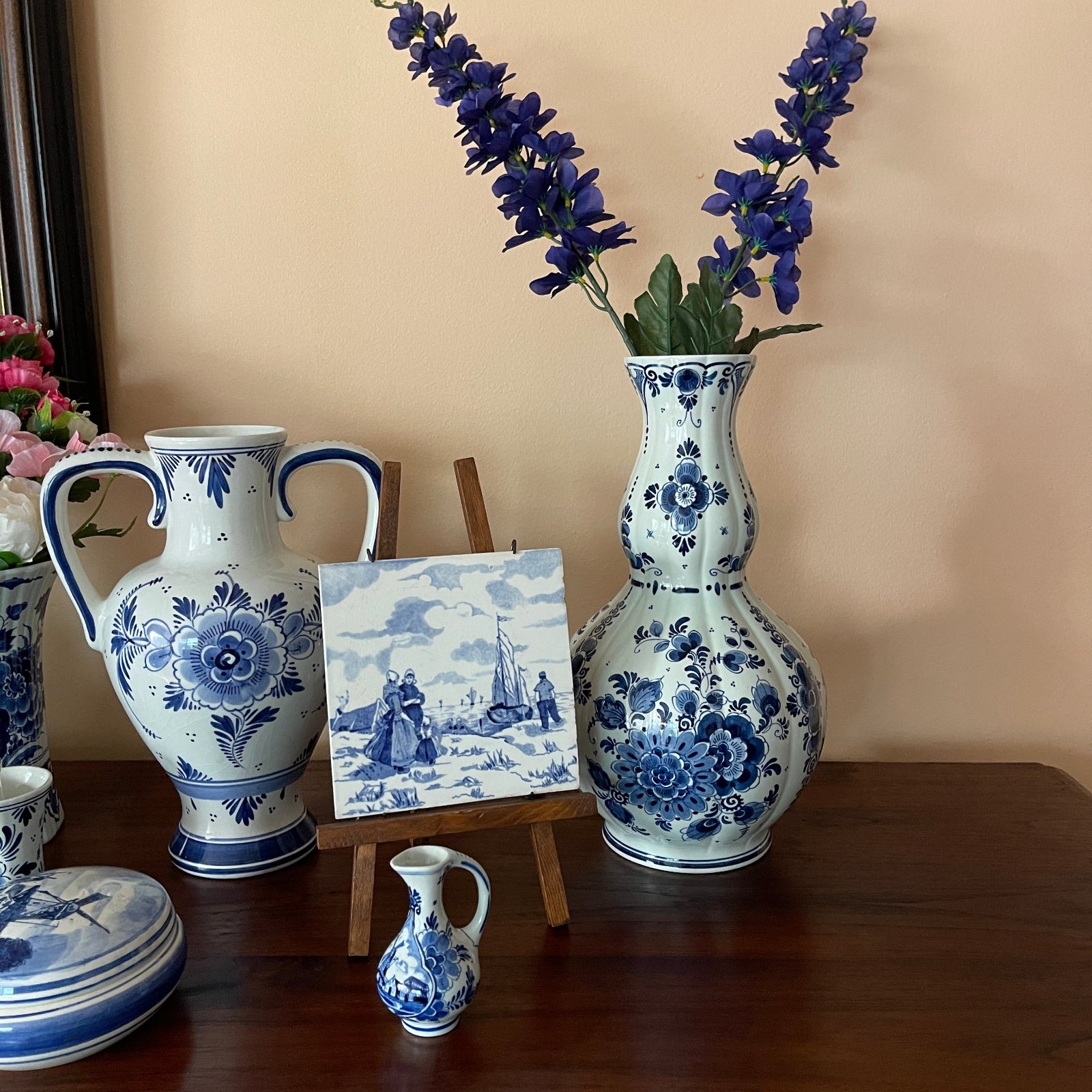 Collection of blue and white ceramic vases and a small painting on a wooden surface.