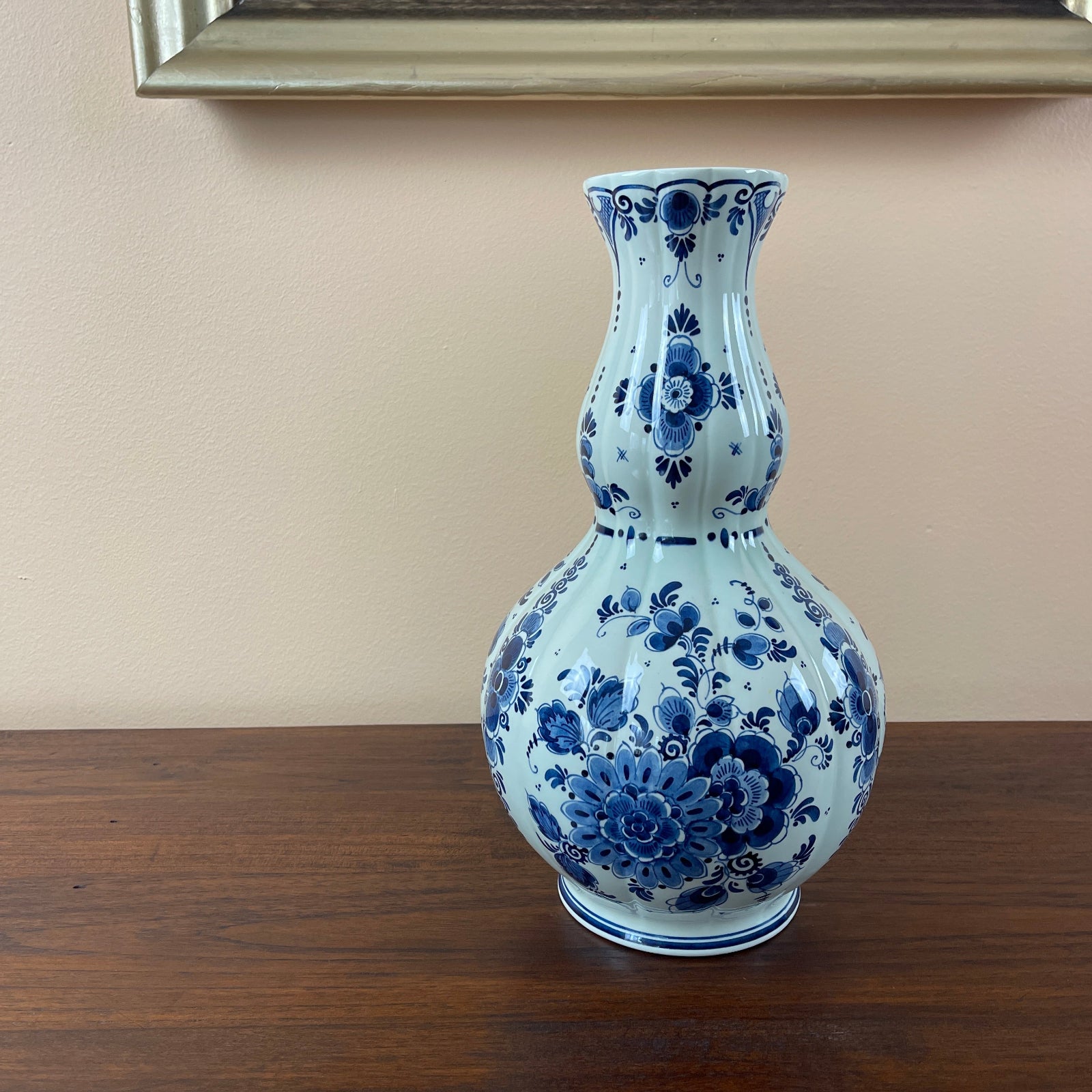 Blue and white floral ceramic vase on a wooden surface with a beige wall background