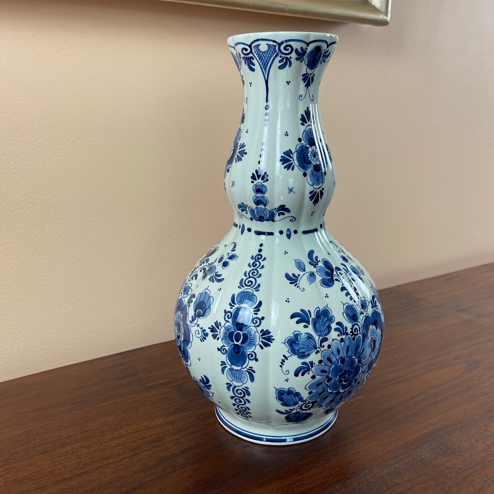 Blue and white floral-patterned vase on a wooden surface with a beige wall background