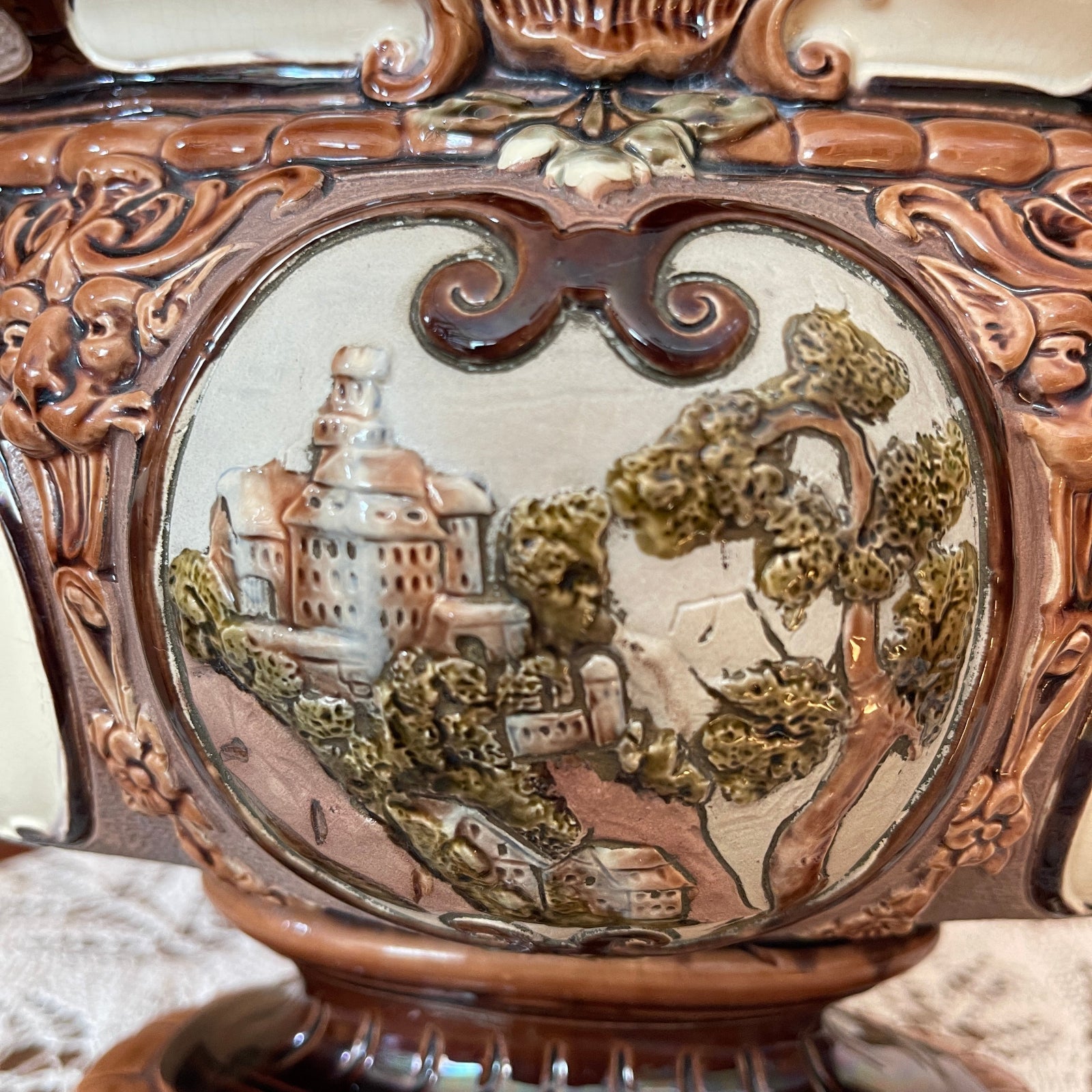 Decorative object with a scenic engraving of a town and trees.