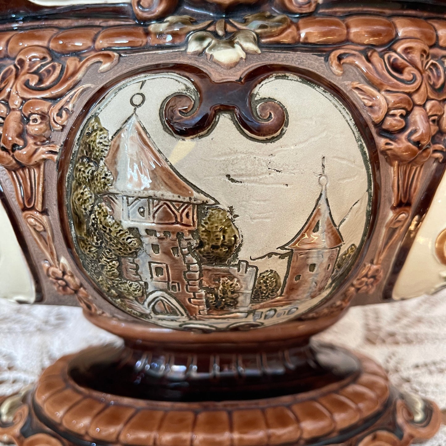 Decorative object with intricate carvings and a small scene of a sailboat and buildings.