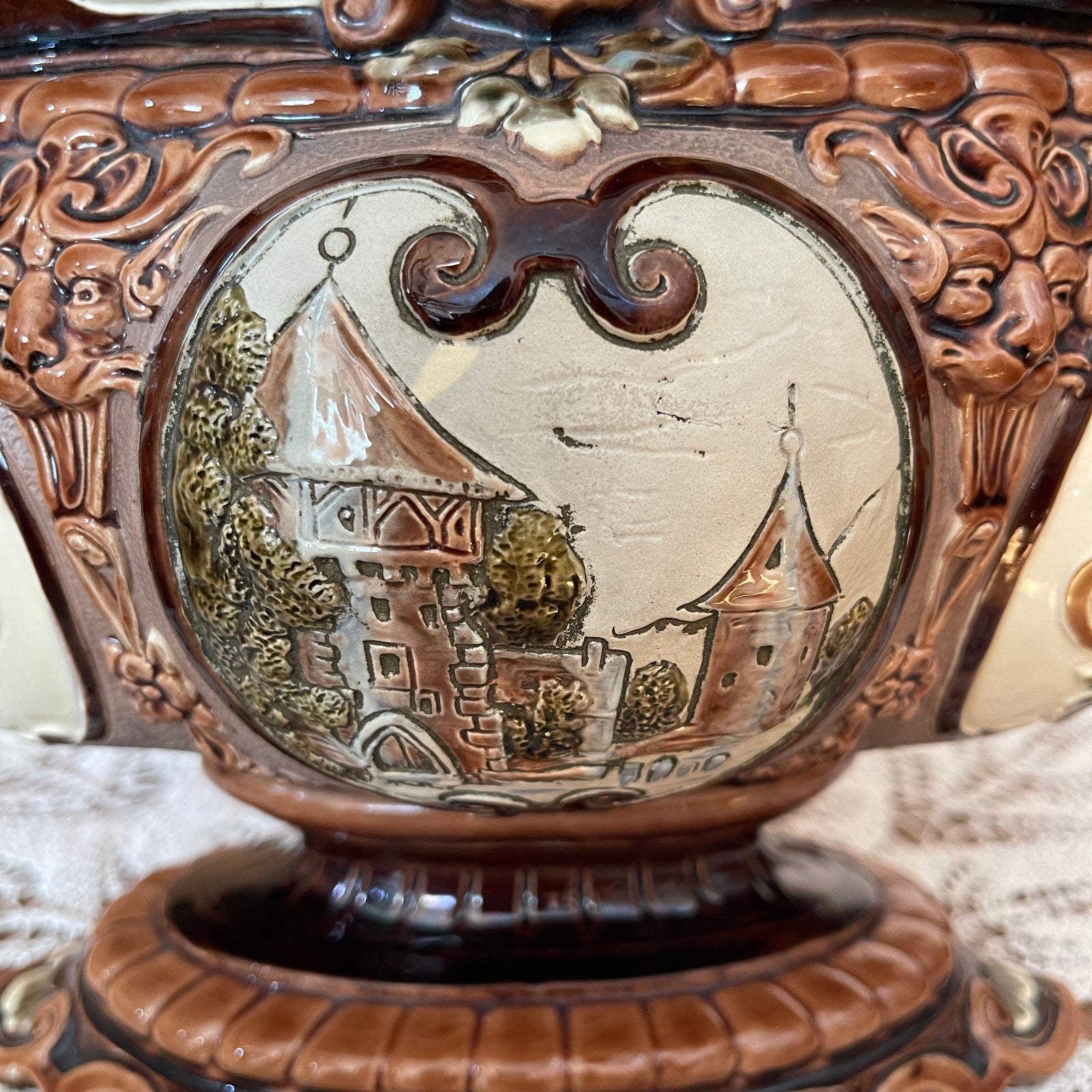 Decorative object with intricate carvings and a small scene of a sailboat and buildings.