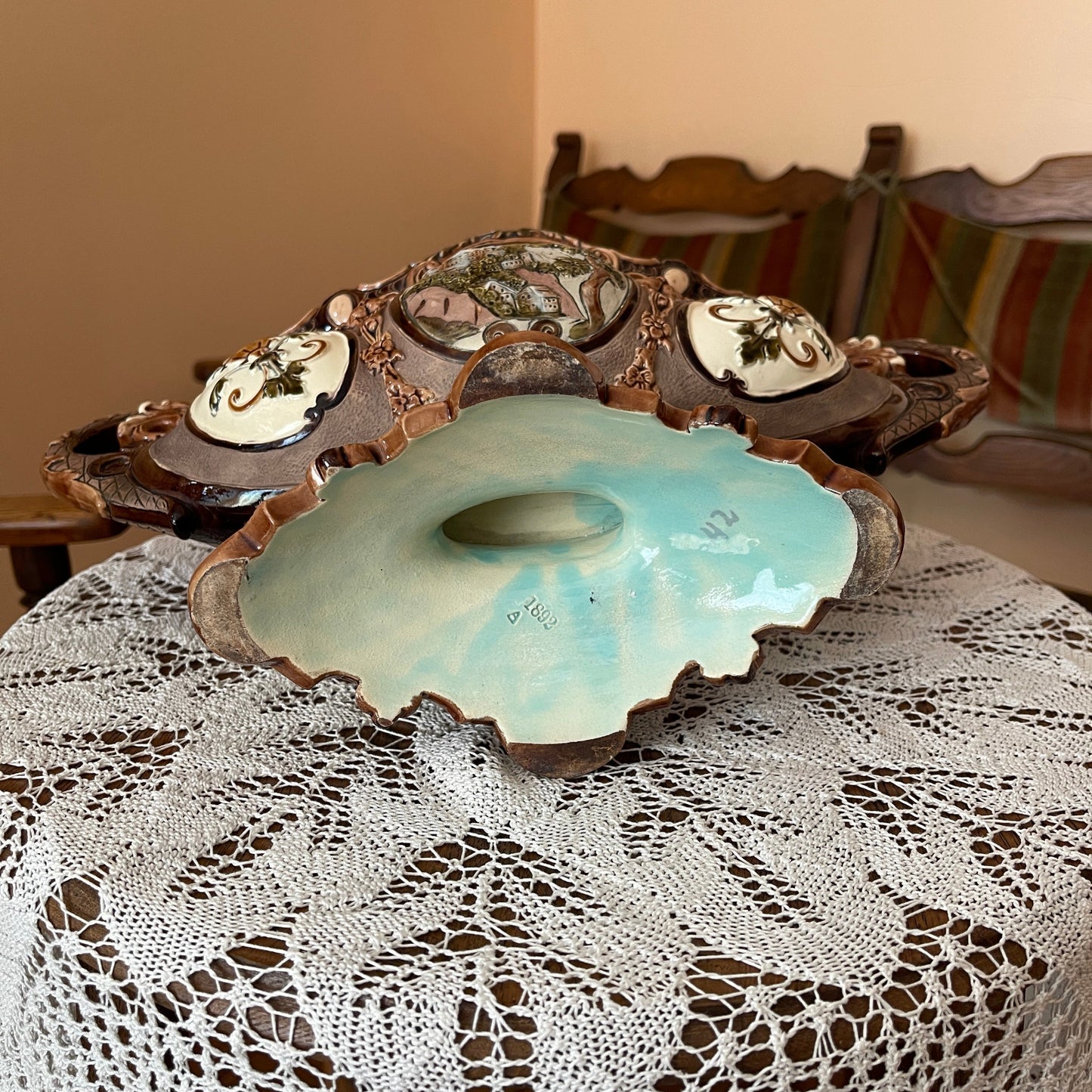Decorative ceramic dish on a lace tablecloth with wooden chairs in the background