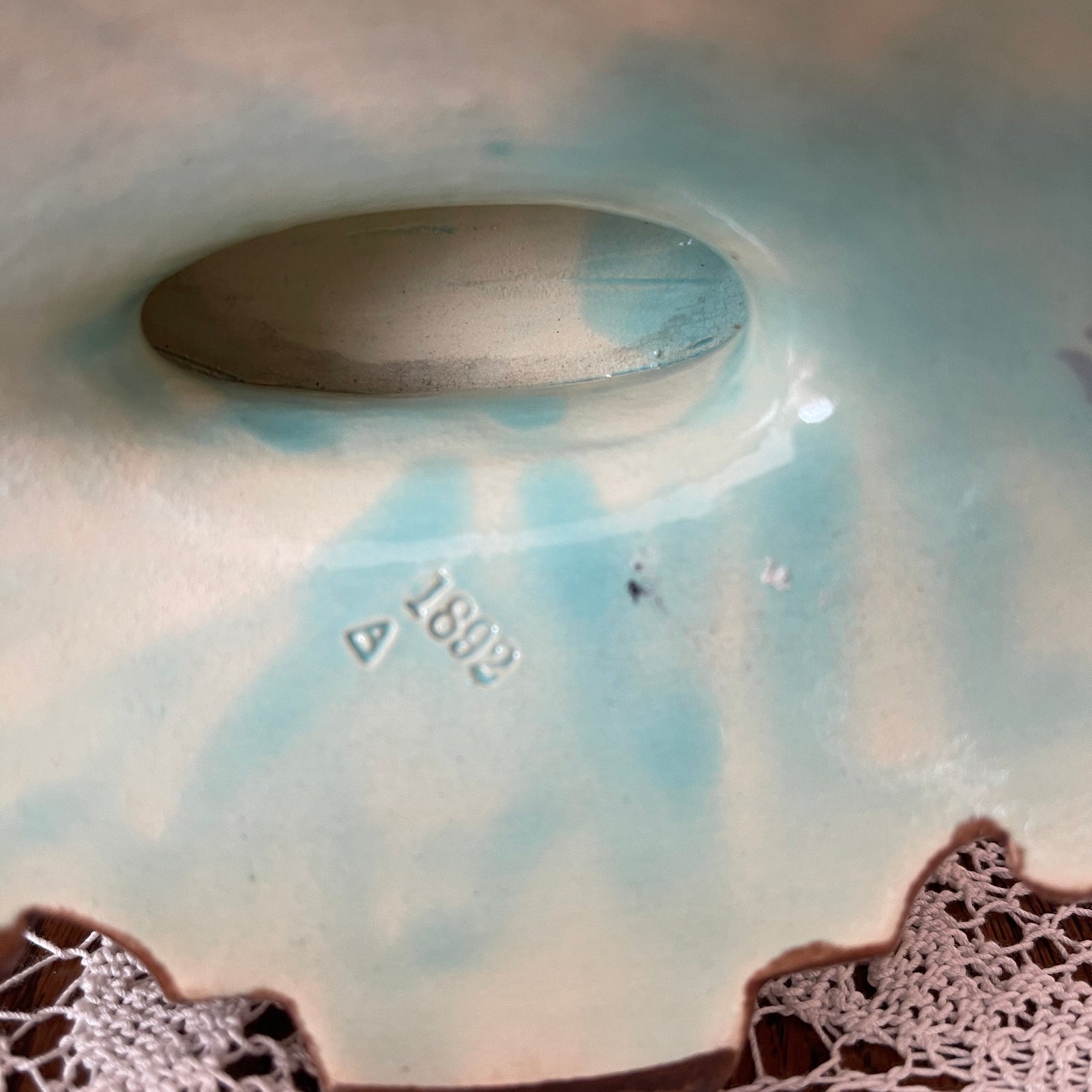 Close-up of a ceramic plate with a textured edge and a visible brand mark.