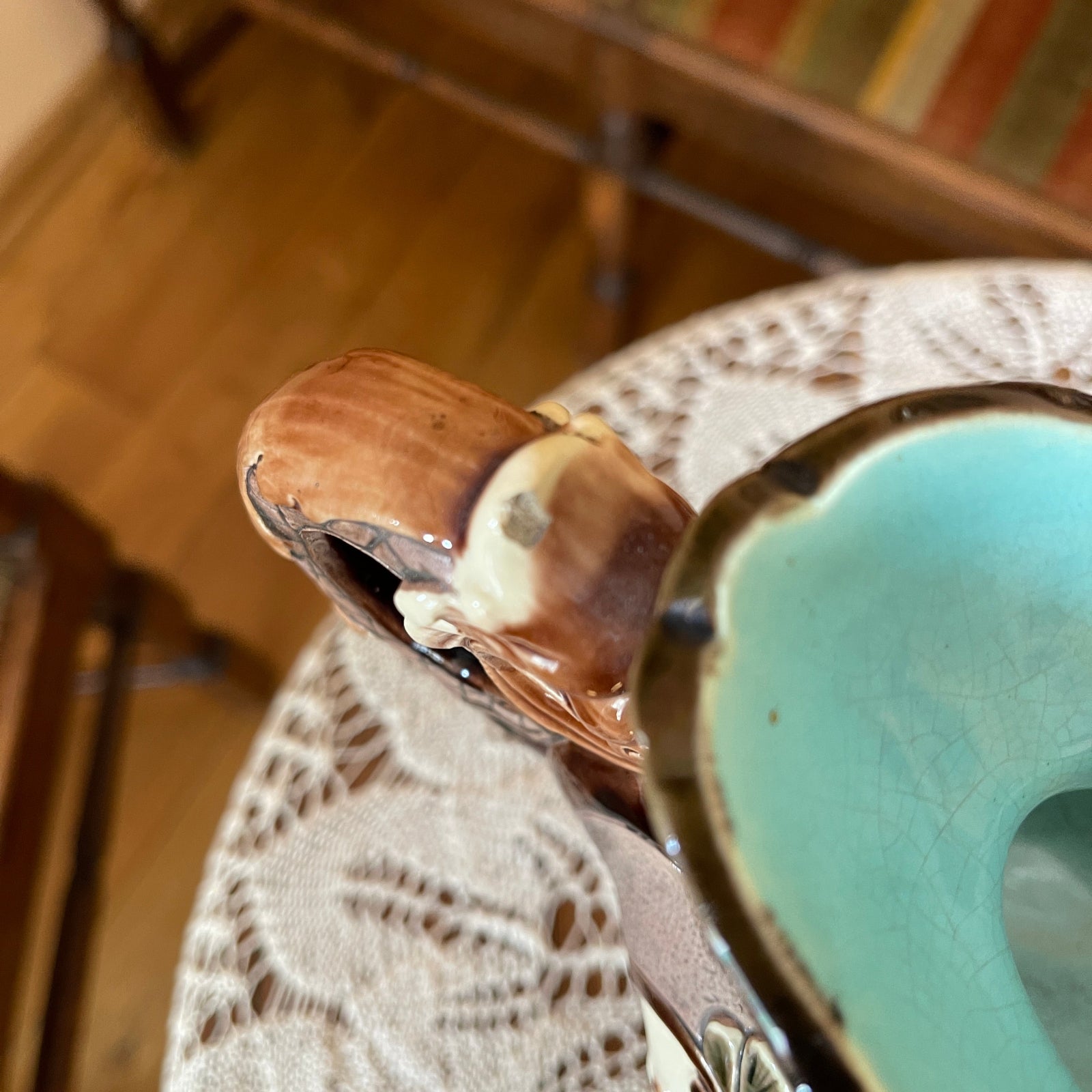 Close-up of a ceramic vase with textured surface and wooden handle on a wooden surface.