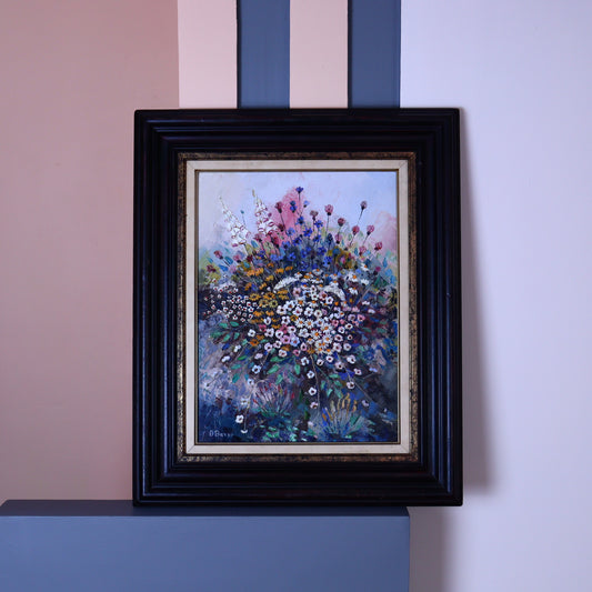 An oil painting of a botanical still life featuring wildflowers, framed in a black frame, placed against a pink and white striped background.