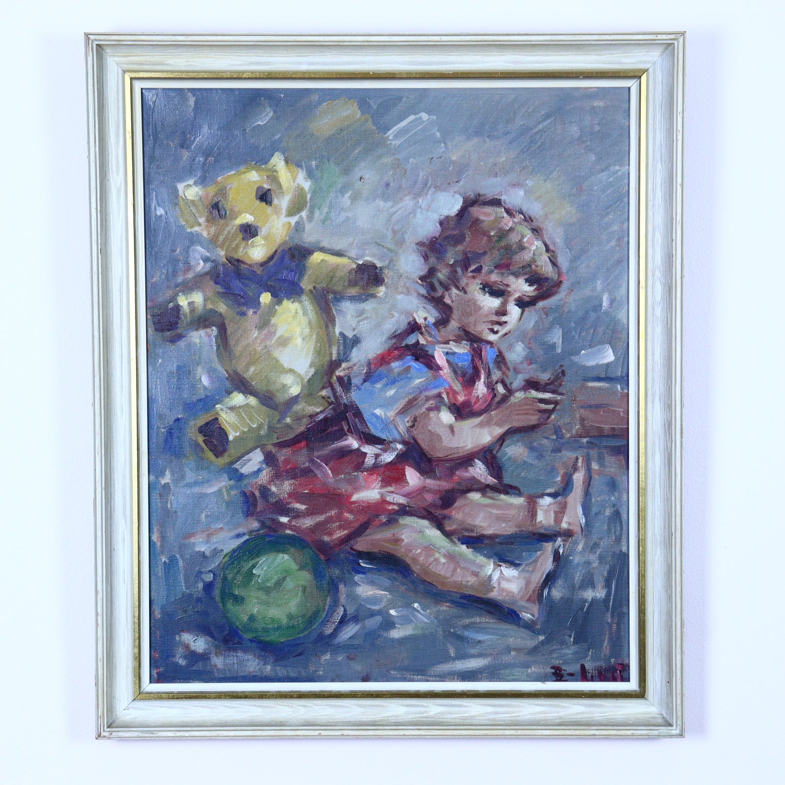 An oil painting of a girl sitting and playing with a teddy bear, framed in a gold frame.