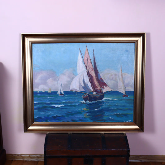 A canvas painting depicting sailboats on a sea, with a gold-painted frame, placed over a wooden chest against a pink wall.