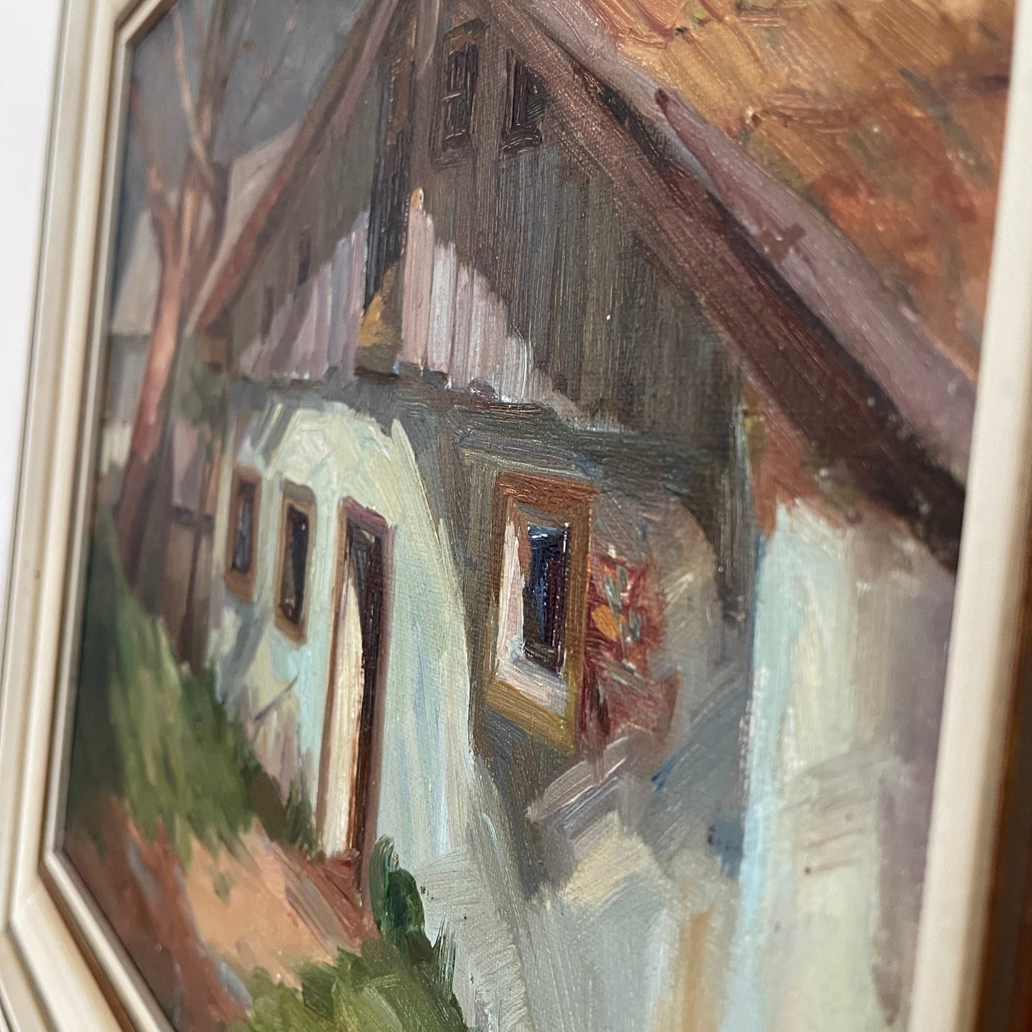 Painting of a house with a sloped roof and windows, framed in a white frame.