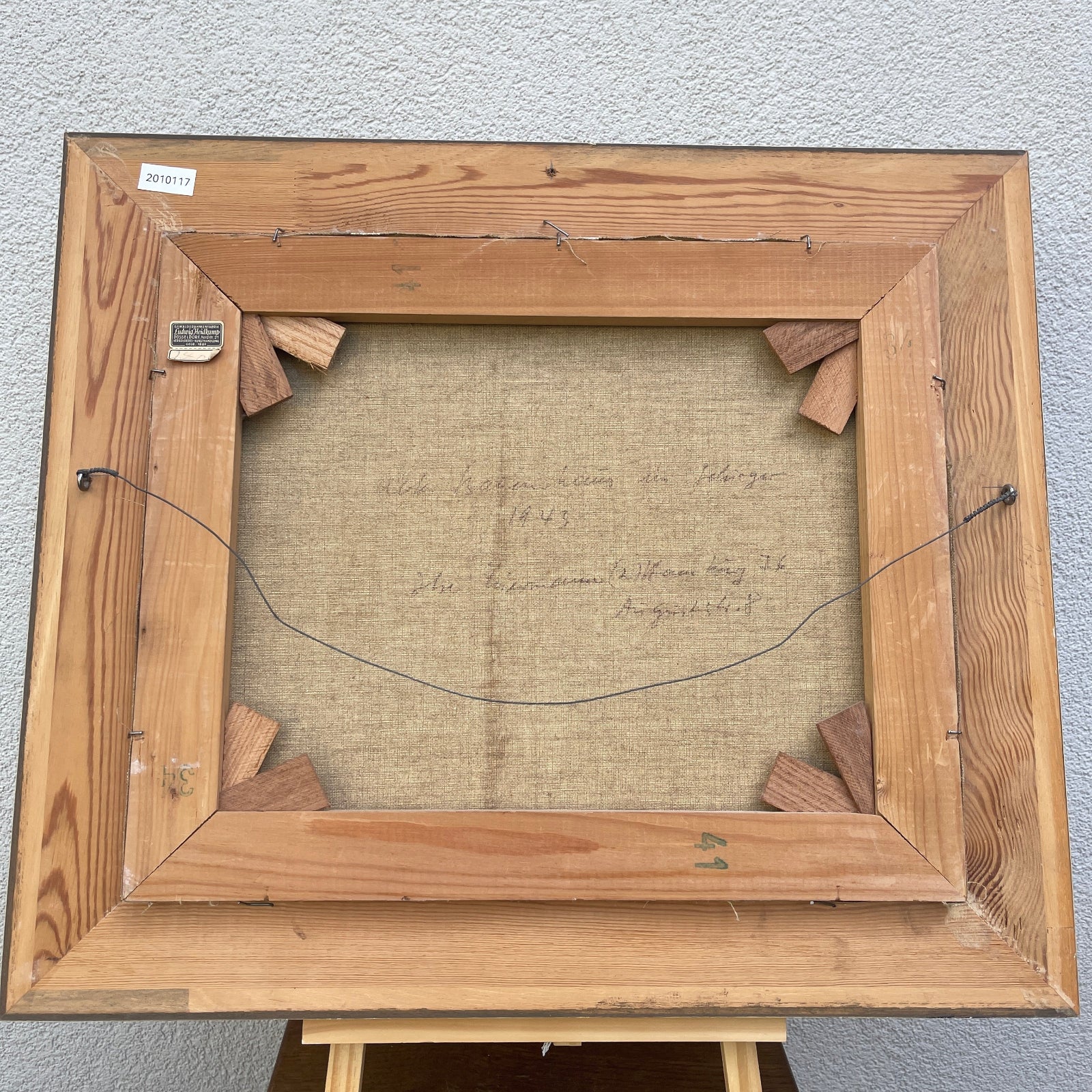 Wooden picture frame with a textured mat and visible signature on a gray background