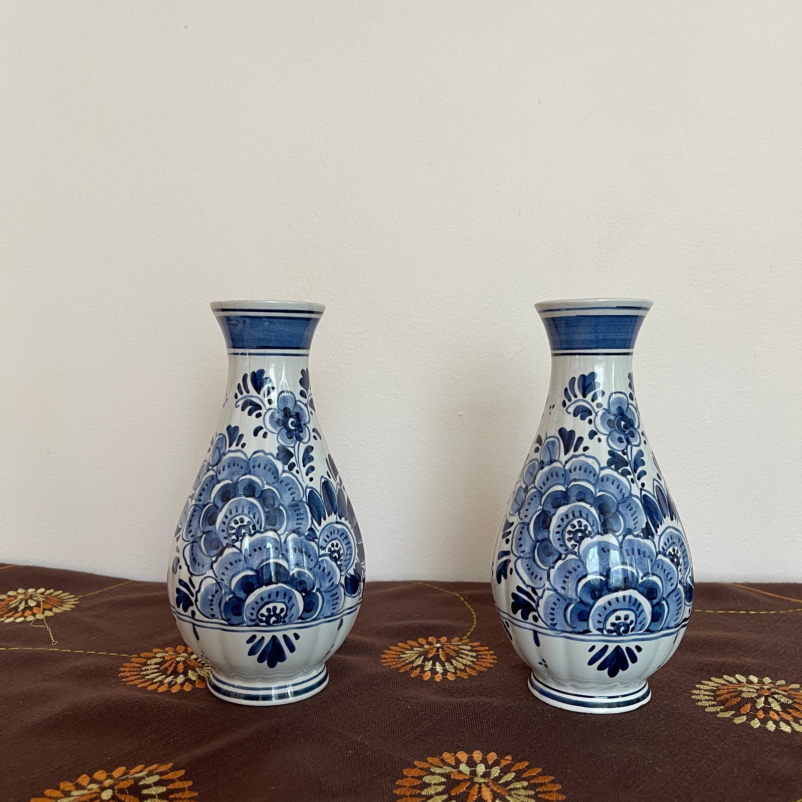 Two blue and white ceramic vases on a patterned surface with a plain background