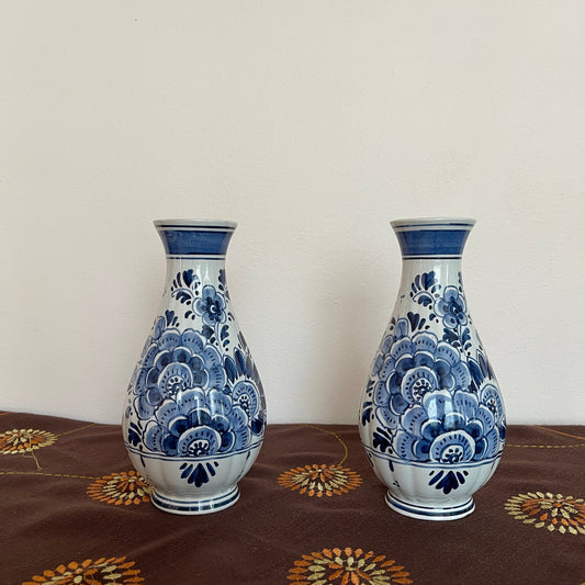 Two blue and white ceramic vases on a patterned surface with a plain background