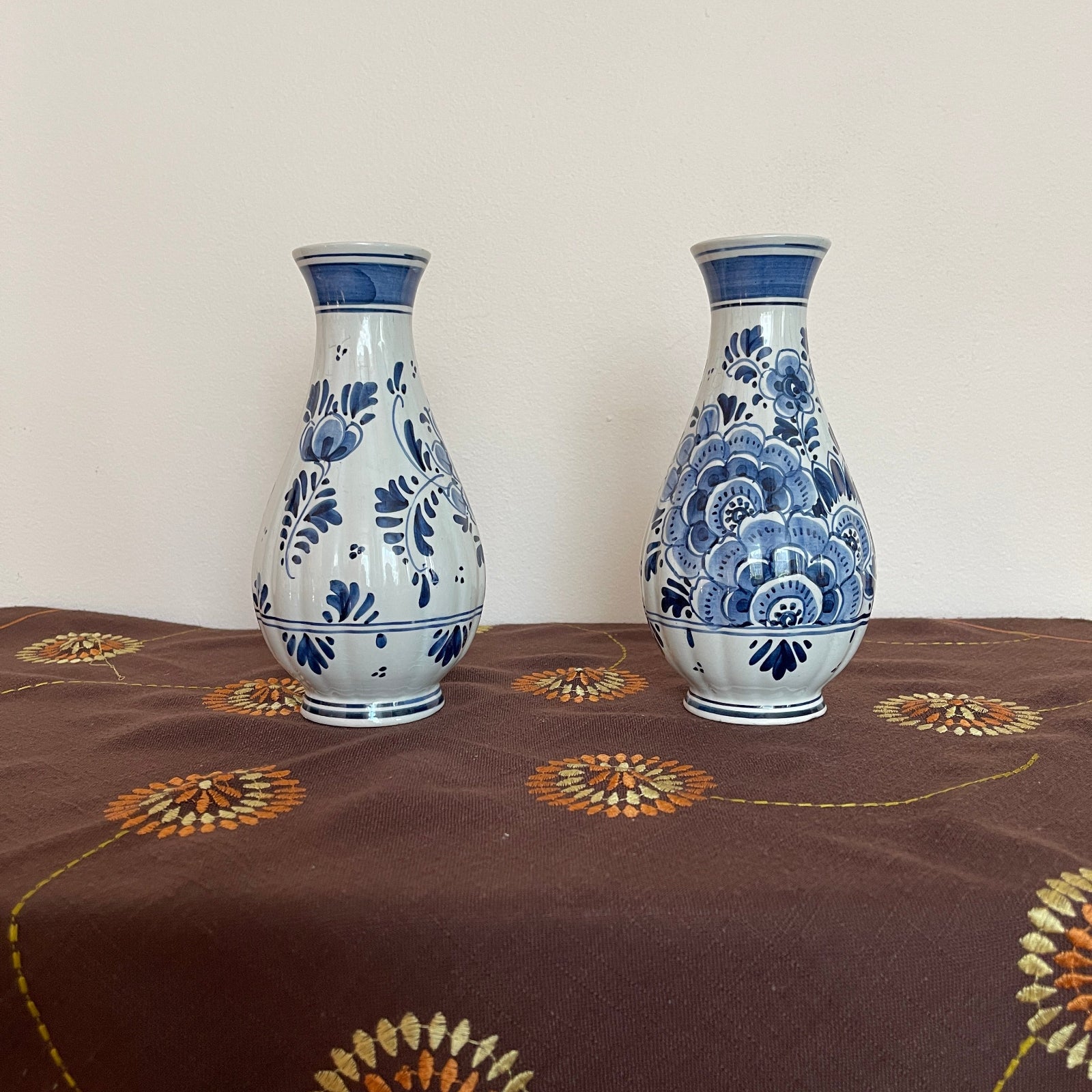 Two blue and white floral-patterned vases on a brown fabric surface with decorative patterns.