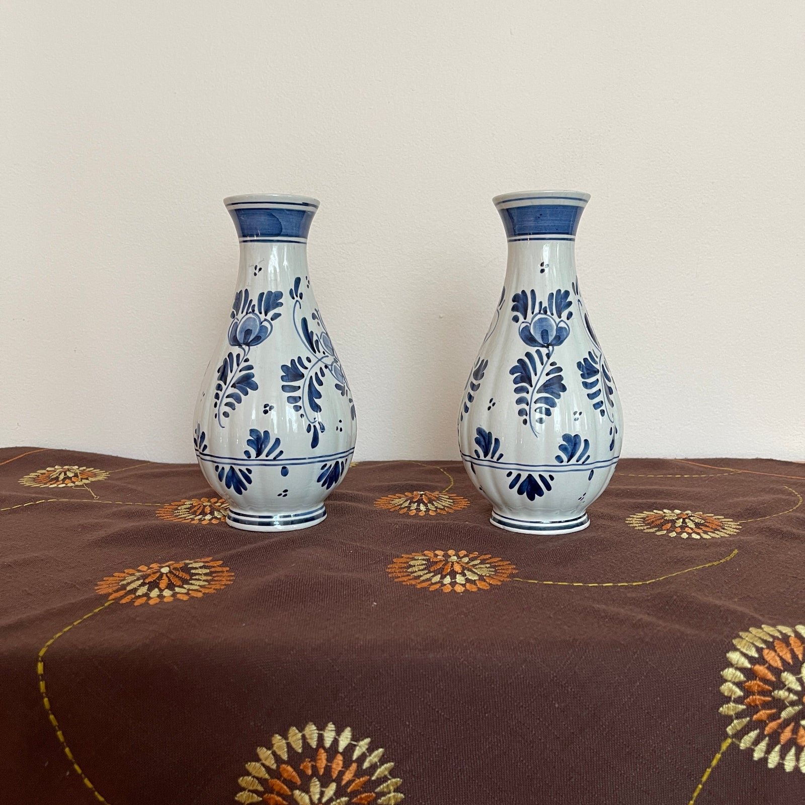 Two ceramic vases with blue floral patterns on a brown fabric surface.