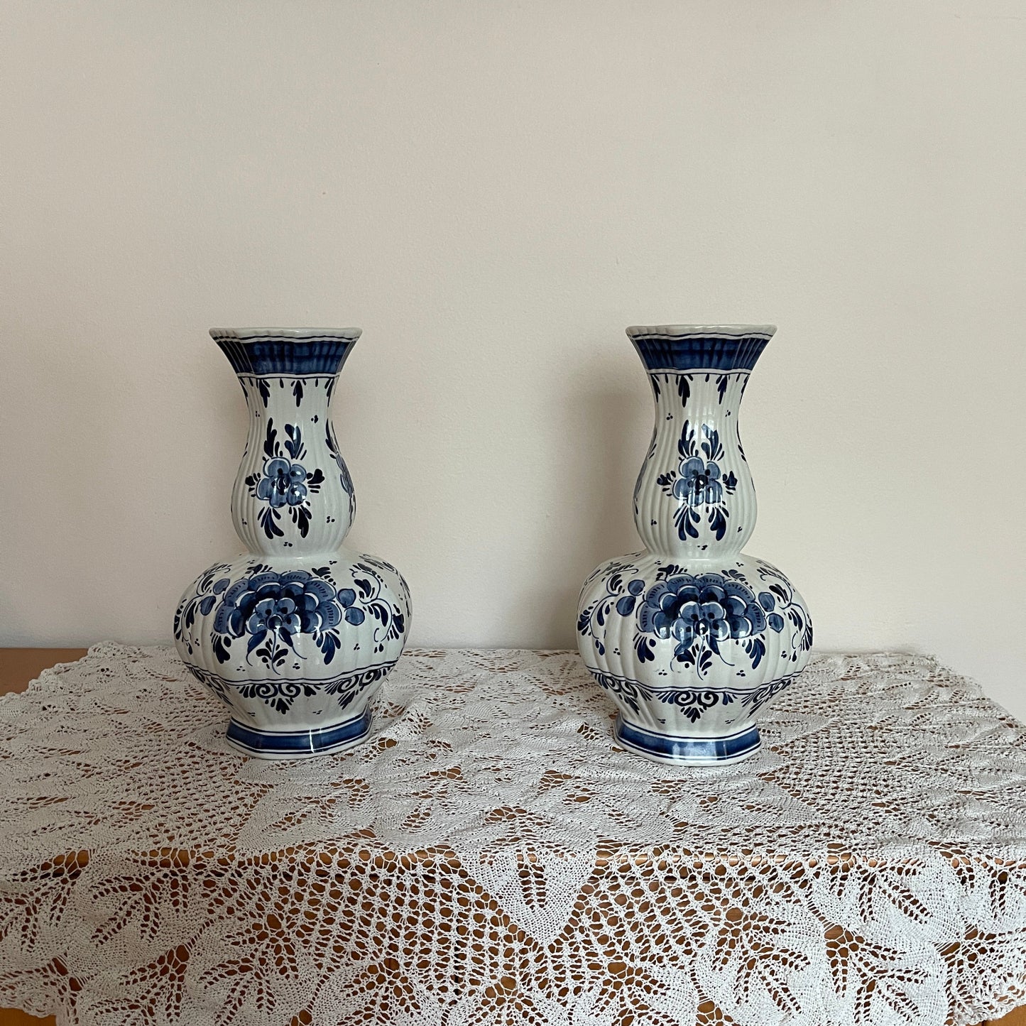 Two blue and white ceramic vases on a lace tablecloth with a plain background