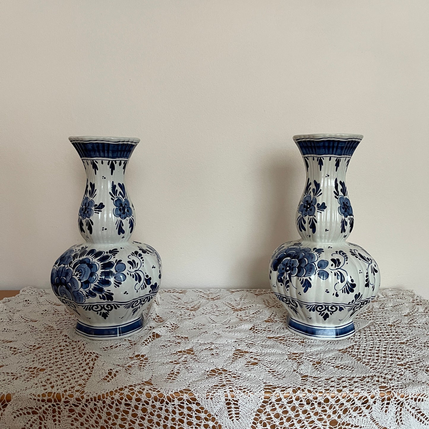 Two blue and white ceramic vases on a lace tablecloth with a plain background