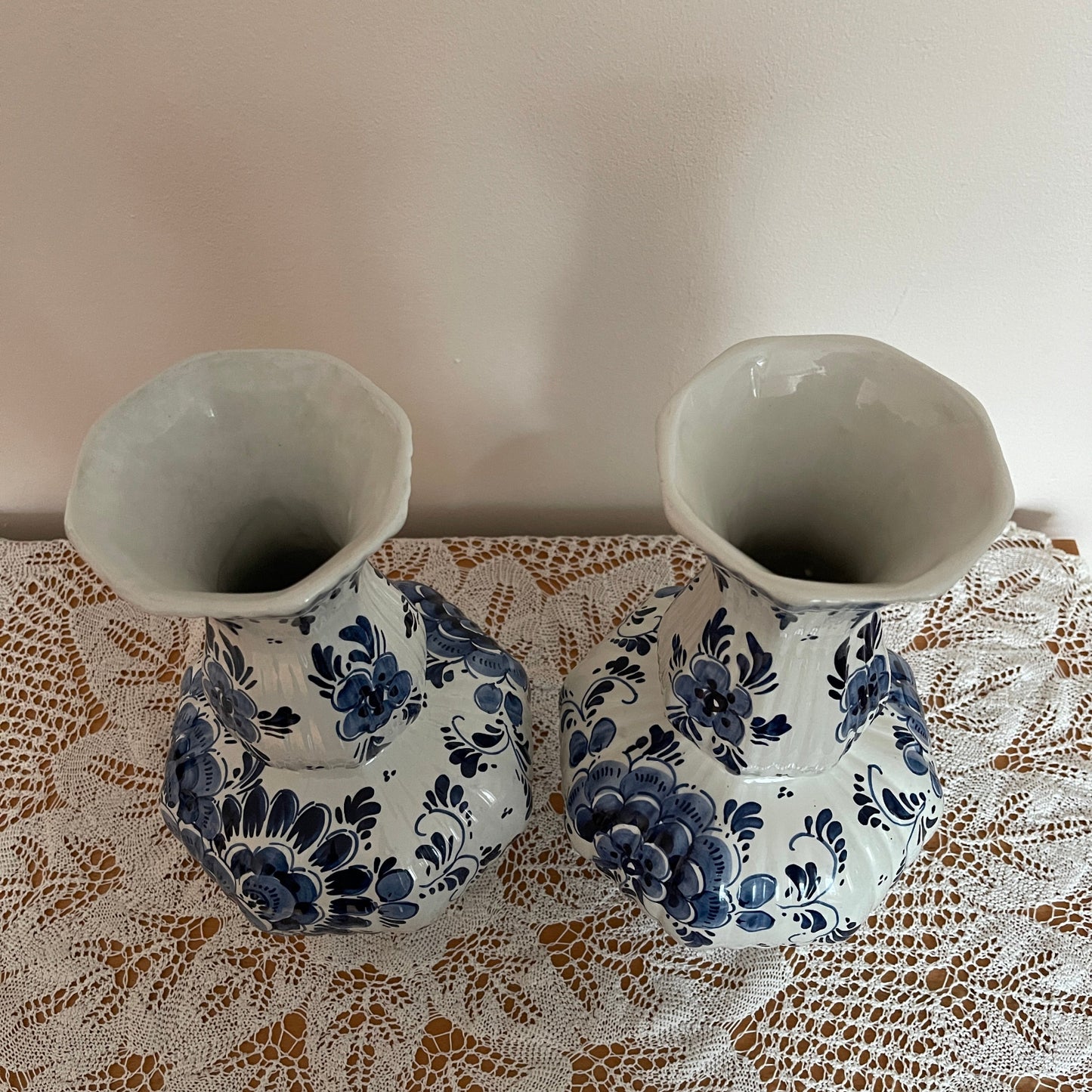Two ceramic vases with blue floral patterns on a lace tablecloth.