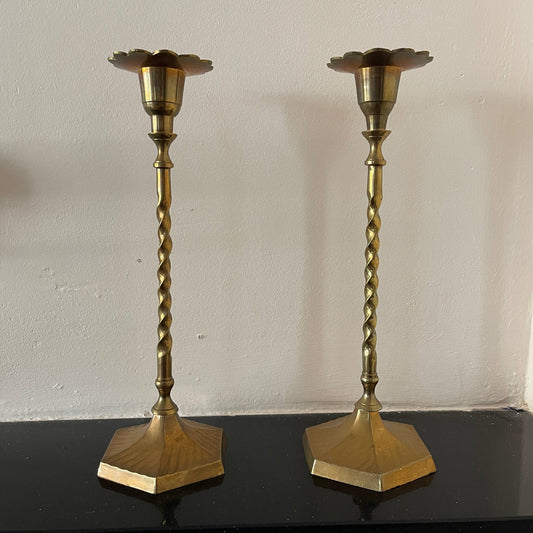Two brass candlesticks with twisted design on a plain background