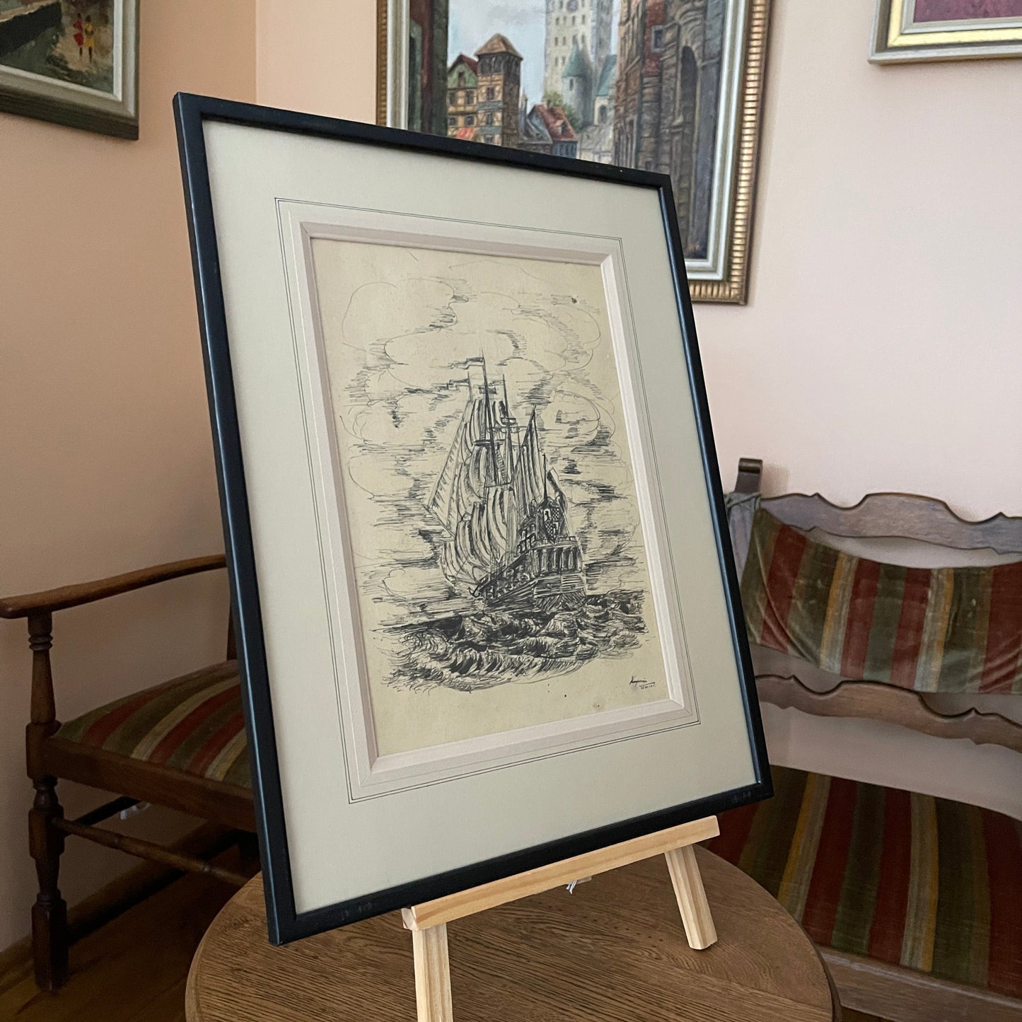 Framed black and white print of a ship on an easel with a room setting in the background