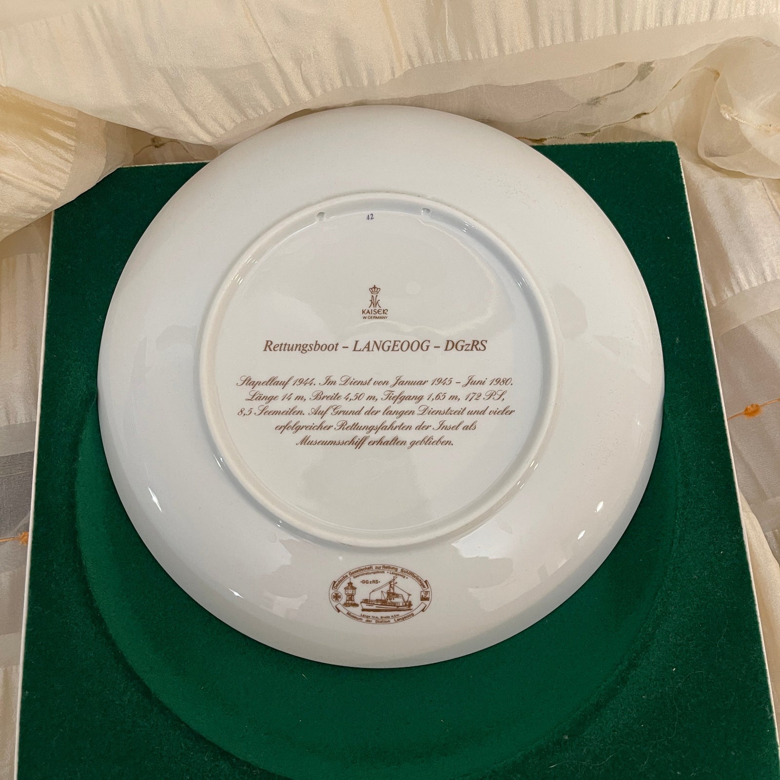 White plate with engraved text and logos on a green cushion