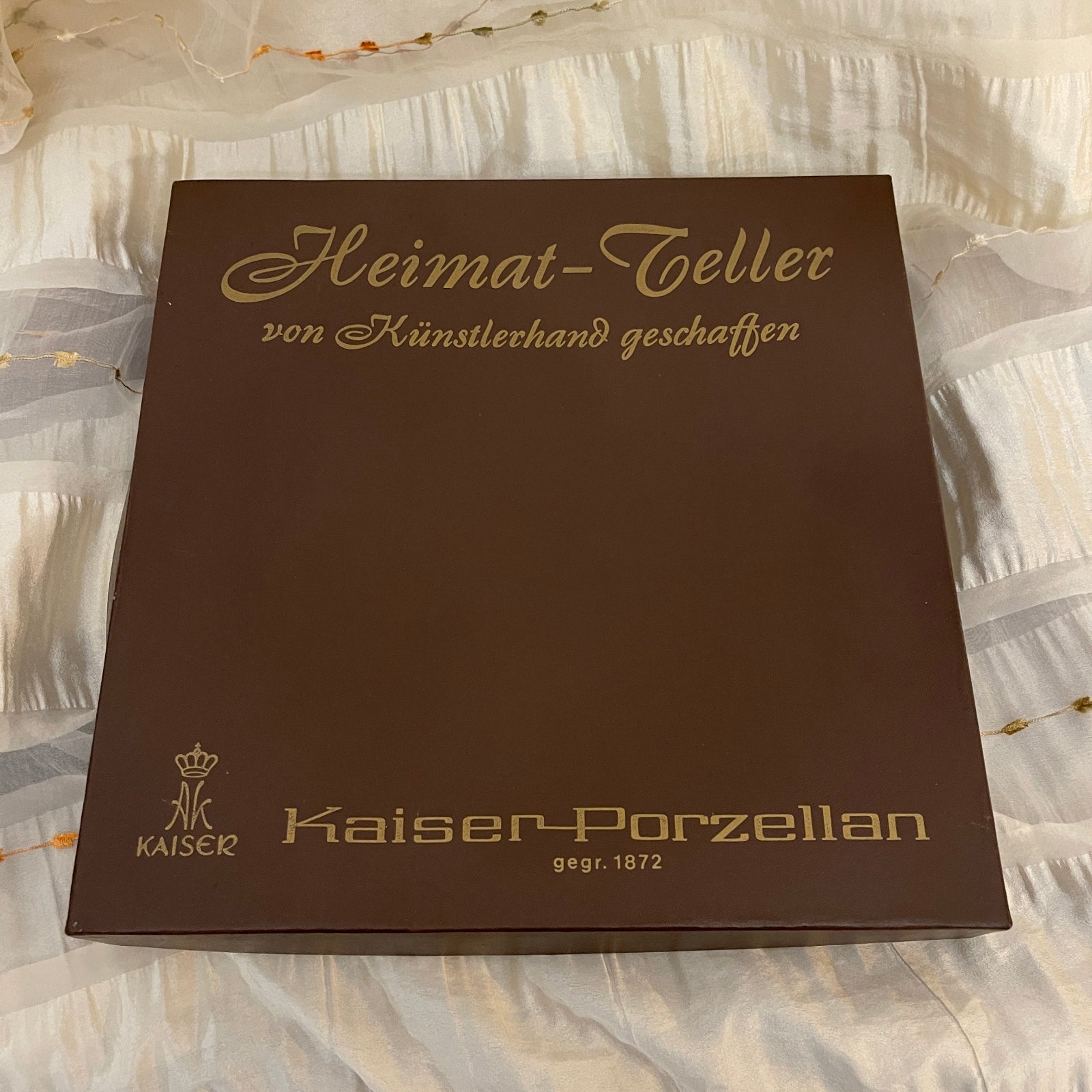 Brown box with gold text and Kaiser Porzellan logo on a textured white background