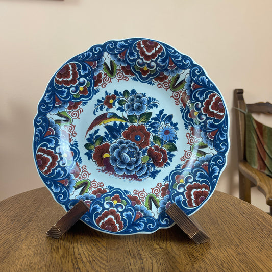 Decorative plate with floral patterns on a stand against a neutral background