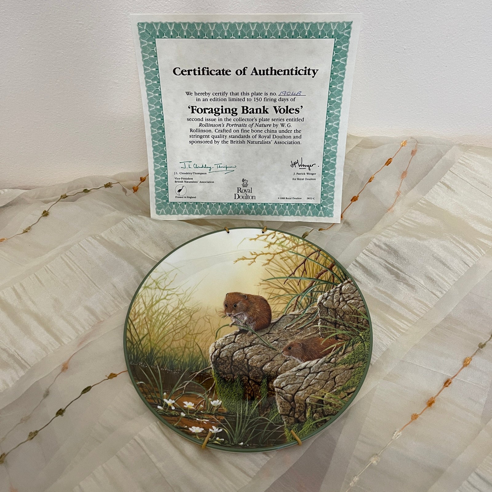 Decorative plate with a mouse design and a certificate of authenticity on a textured surface.