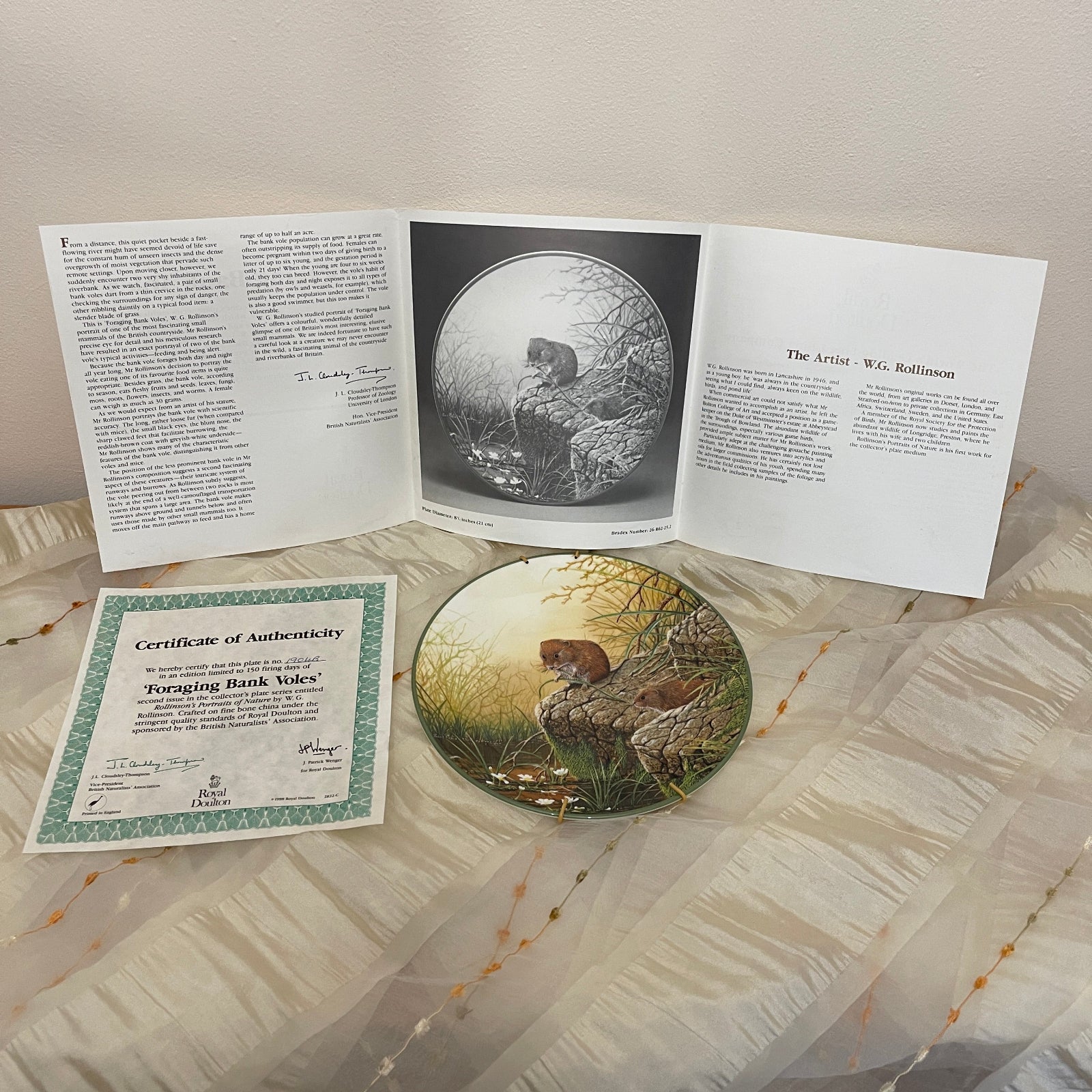 Open book with illustrations and a certificate of authenticity on a textured surface