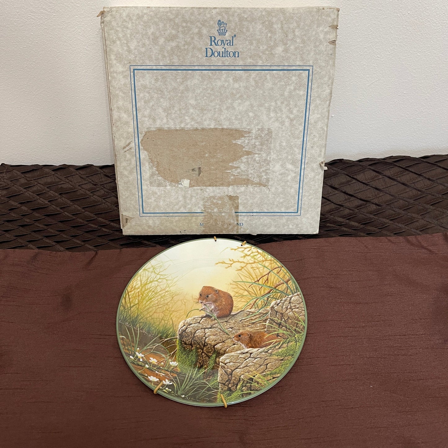 Decorative plate with animal design on a brown surface, featuring Royal Doulton branding.