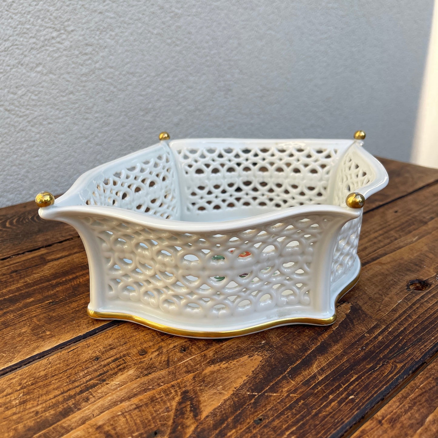 Decorative white basket with gold accents on a wooden surface