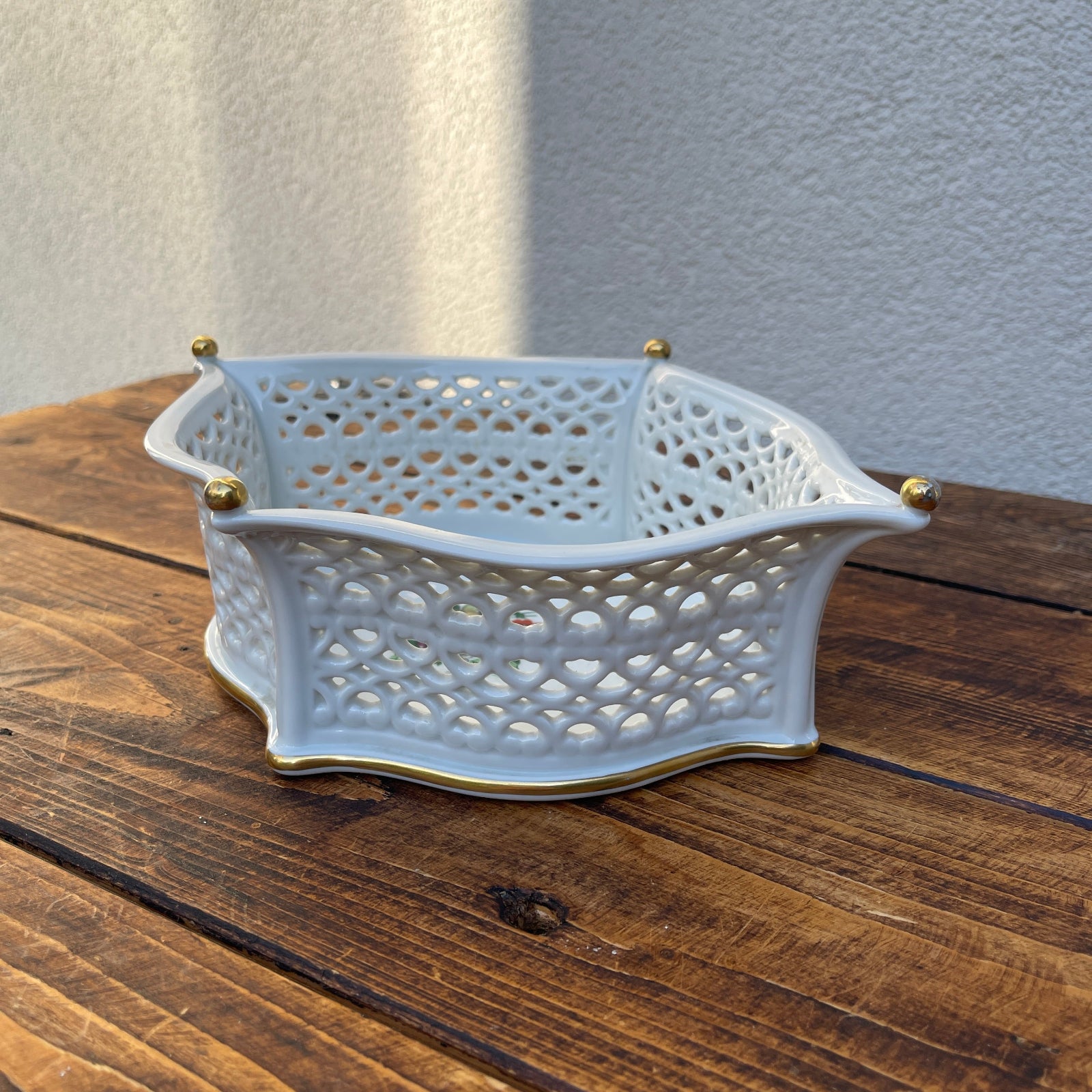 Decorative ceramic basket with gold accents on a wooden surface