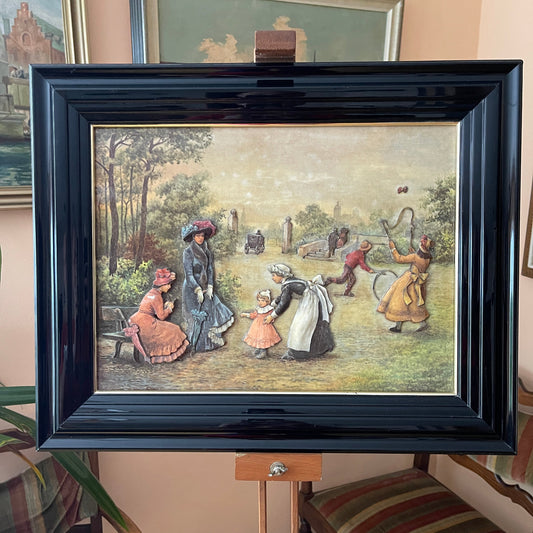 Framed artwork depicting a scene with people in a park, on a stand.