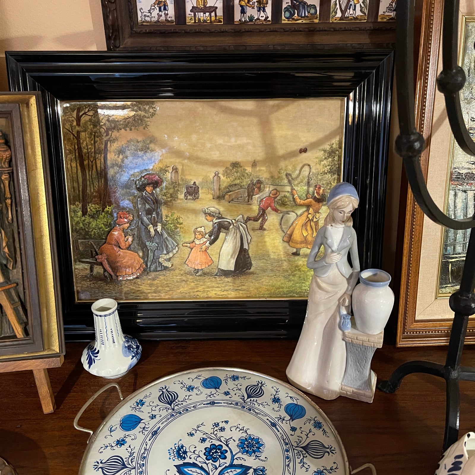 Framed artwork of a historical scene with decorative items on a wooden surface.