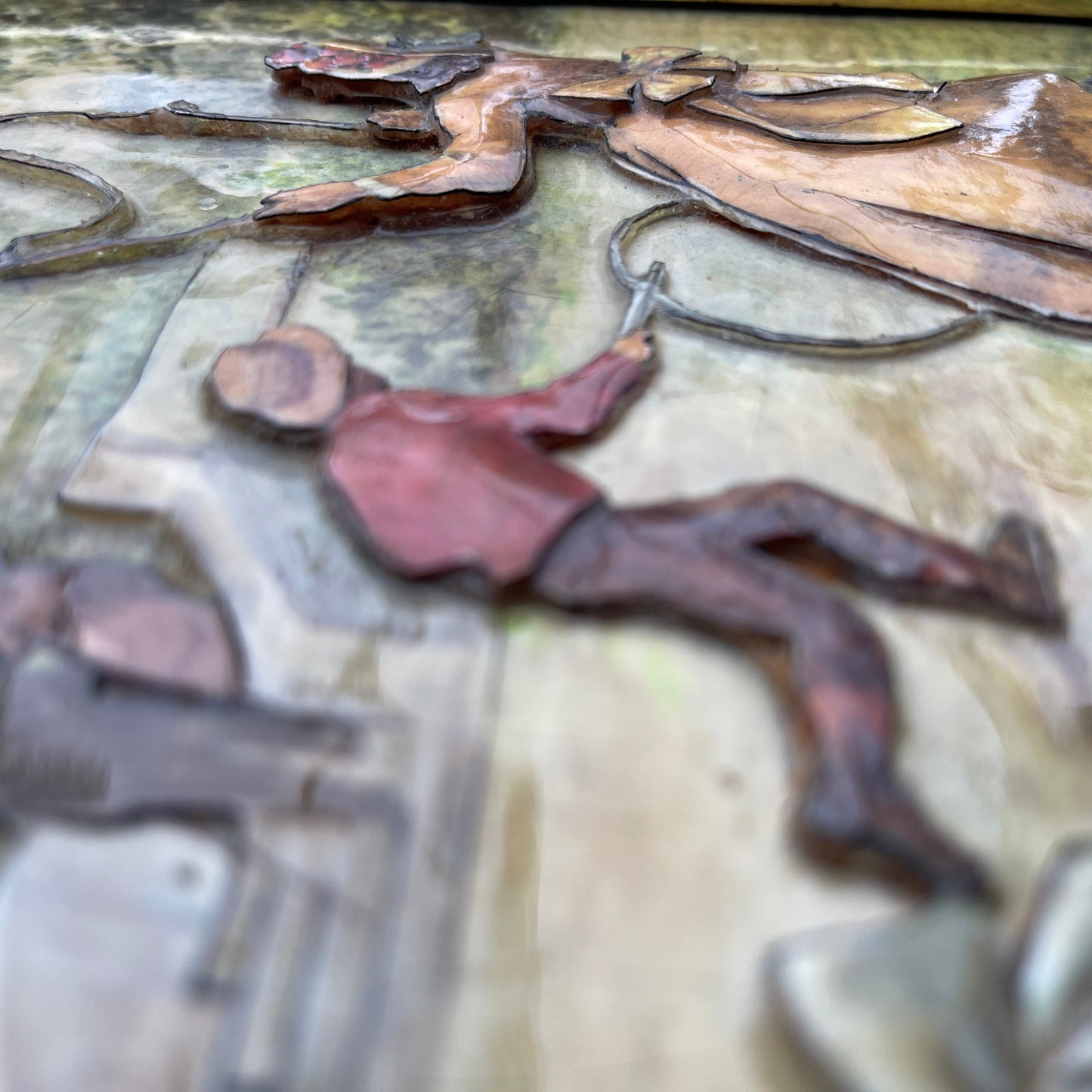 Metallic sculpture of a person with tools on a textured surface
