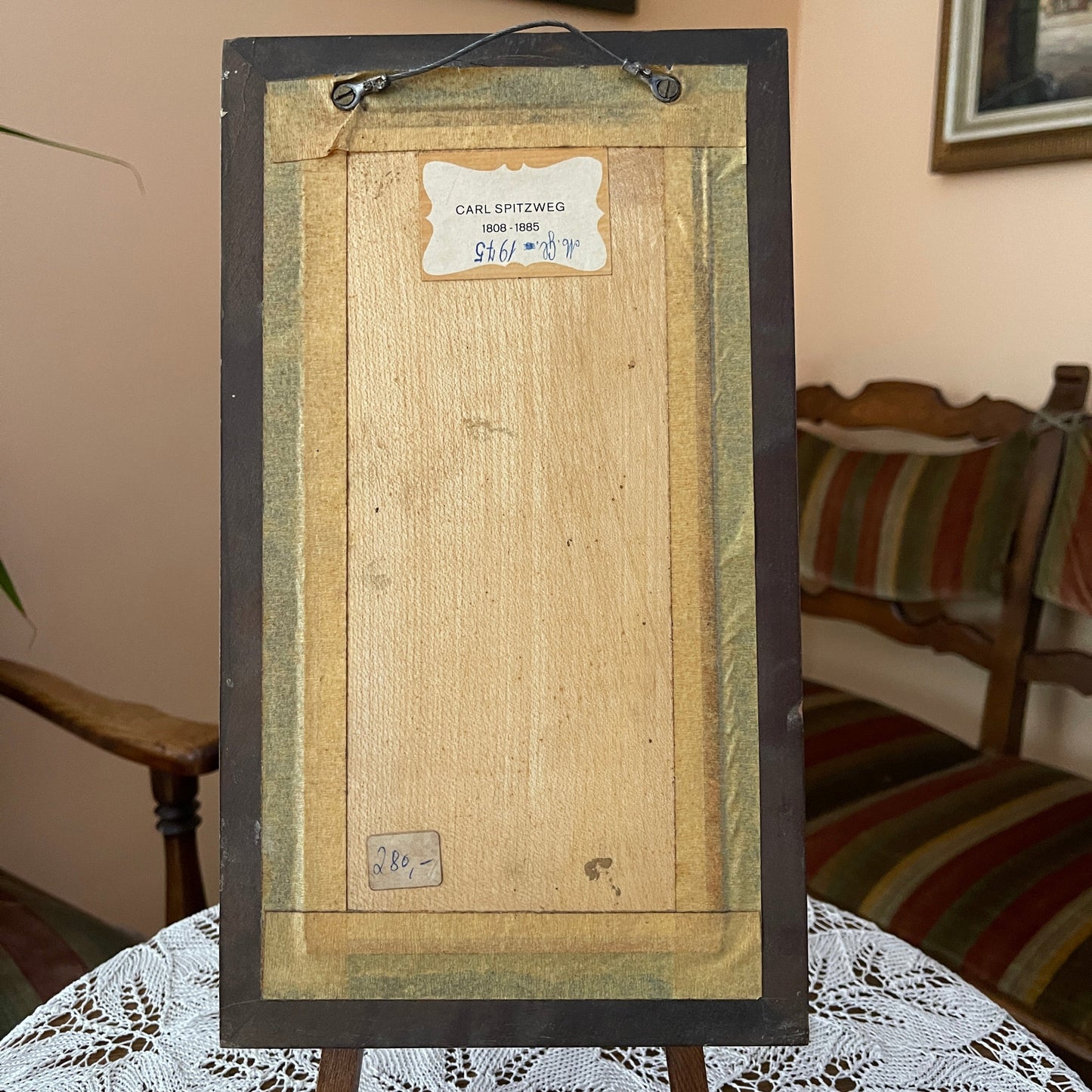 Back of a framed artwork with visible signature and details on a table.