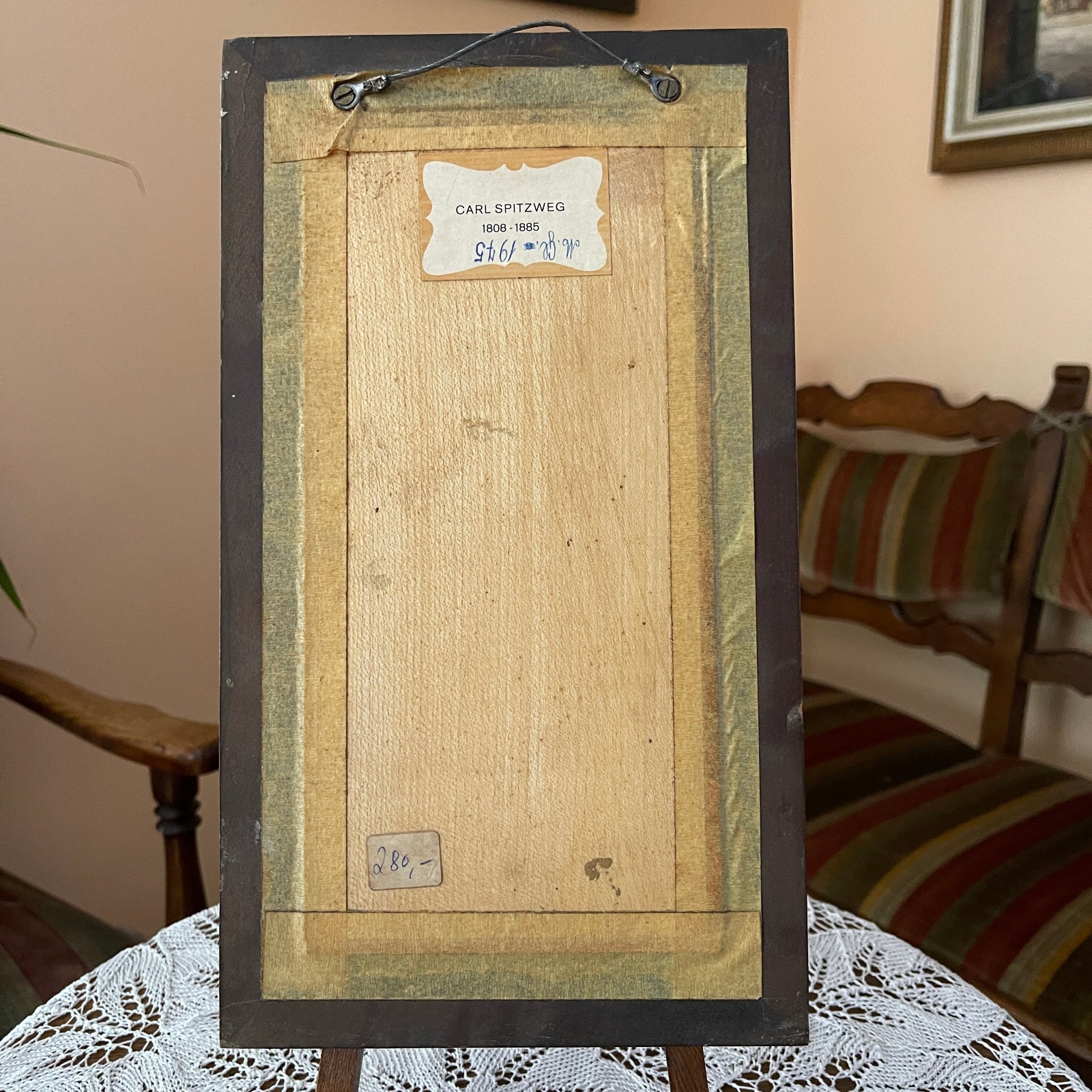 Back of a framed artwork with visible signature and details on a table.