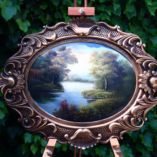 Decorative oval mirror with ornate bronze frame on a green leafy background