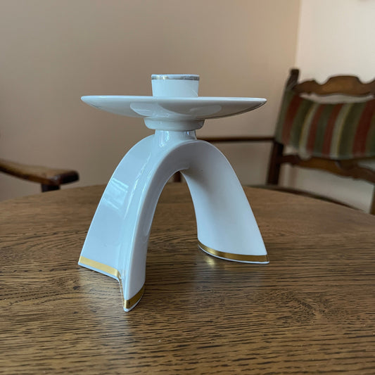White ceramic candle holder on a wooden table with a blurred background