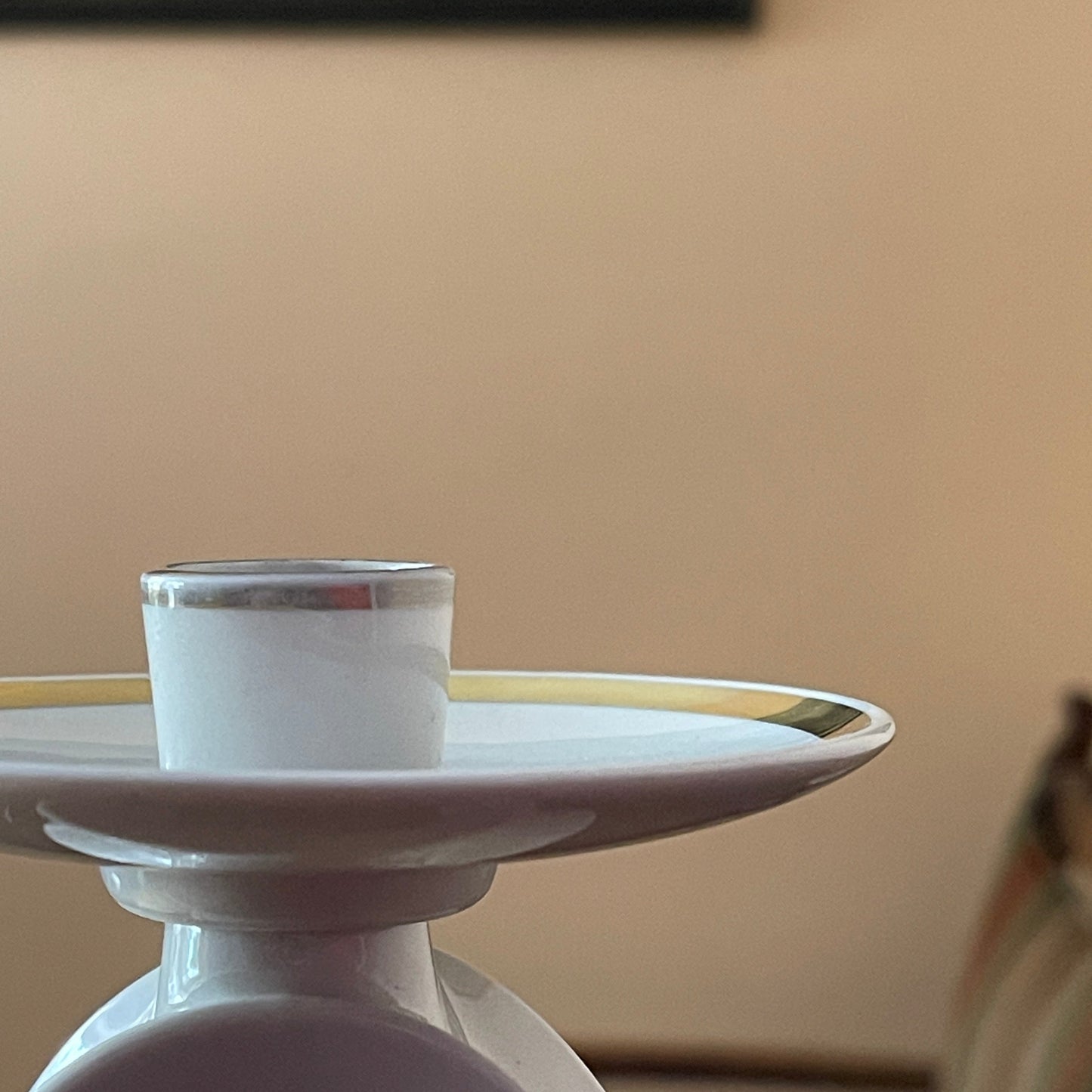 White candle holder with a silver base on a beige background