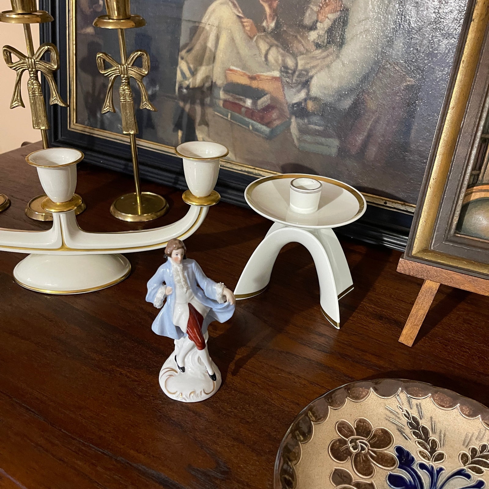 Decorative items including a figurine, candle holders, and a painting on a wooden surface.