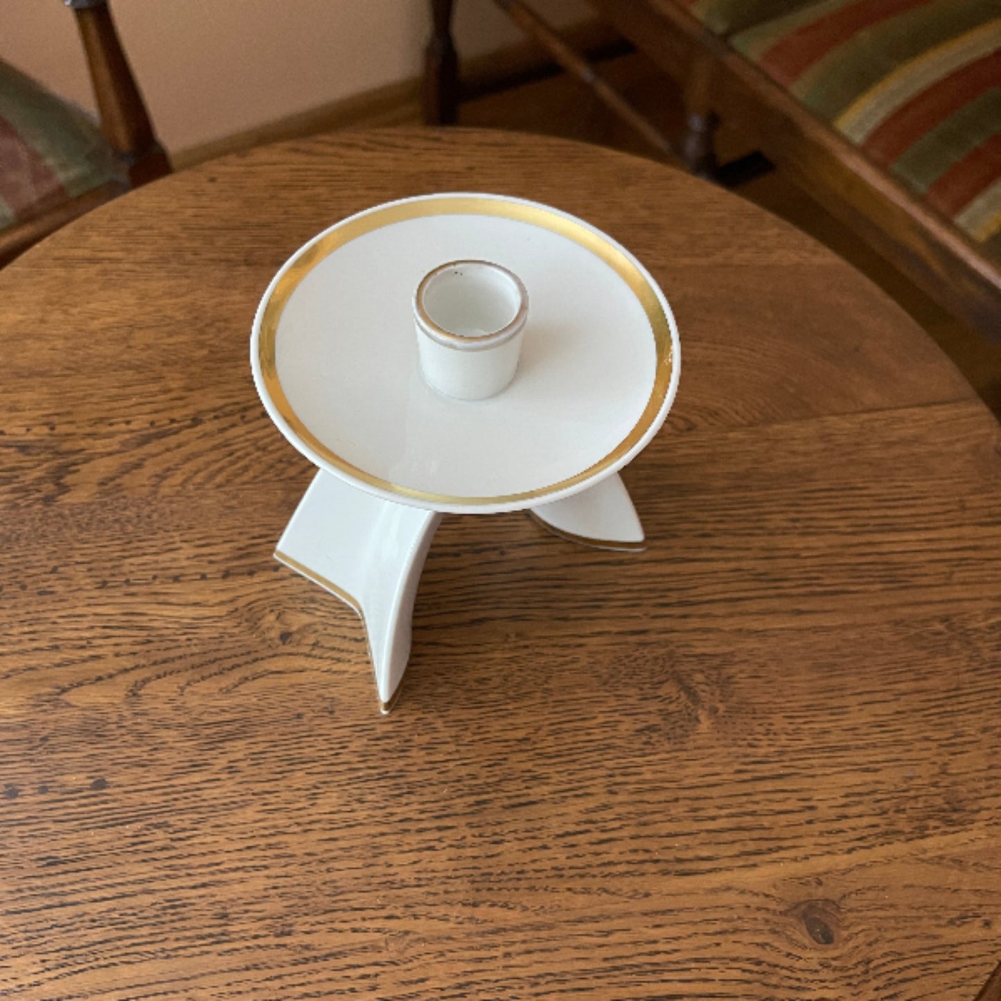 White ceramic candle holder with gold rim on a wooden table