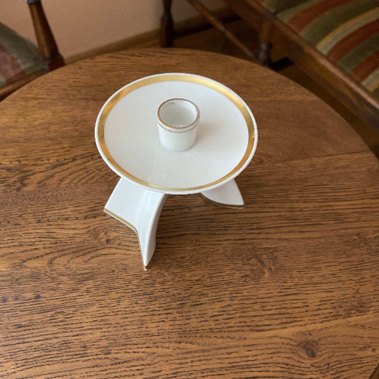 White ceramic candle holder with gold rim on a wooden table