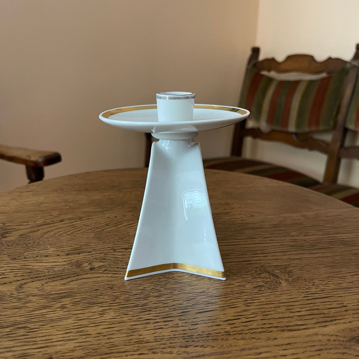 White ceramic candle holder with gold accents on a wooden table