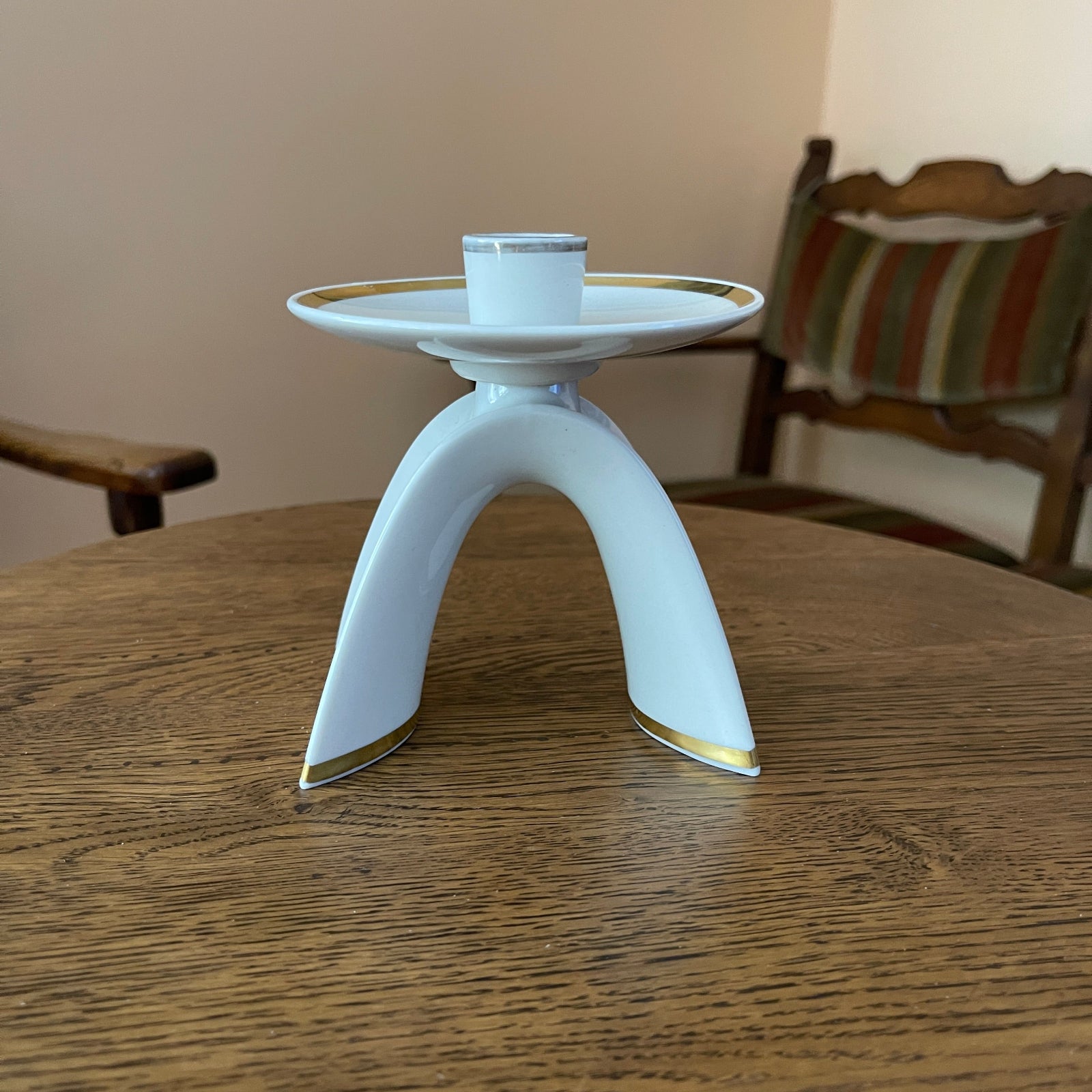 White ceramic candle holder with gold accents on a wooden table