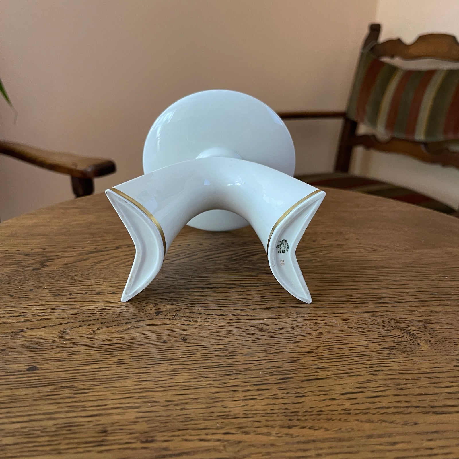 White ceramic vase with gold accents on a wooden table