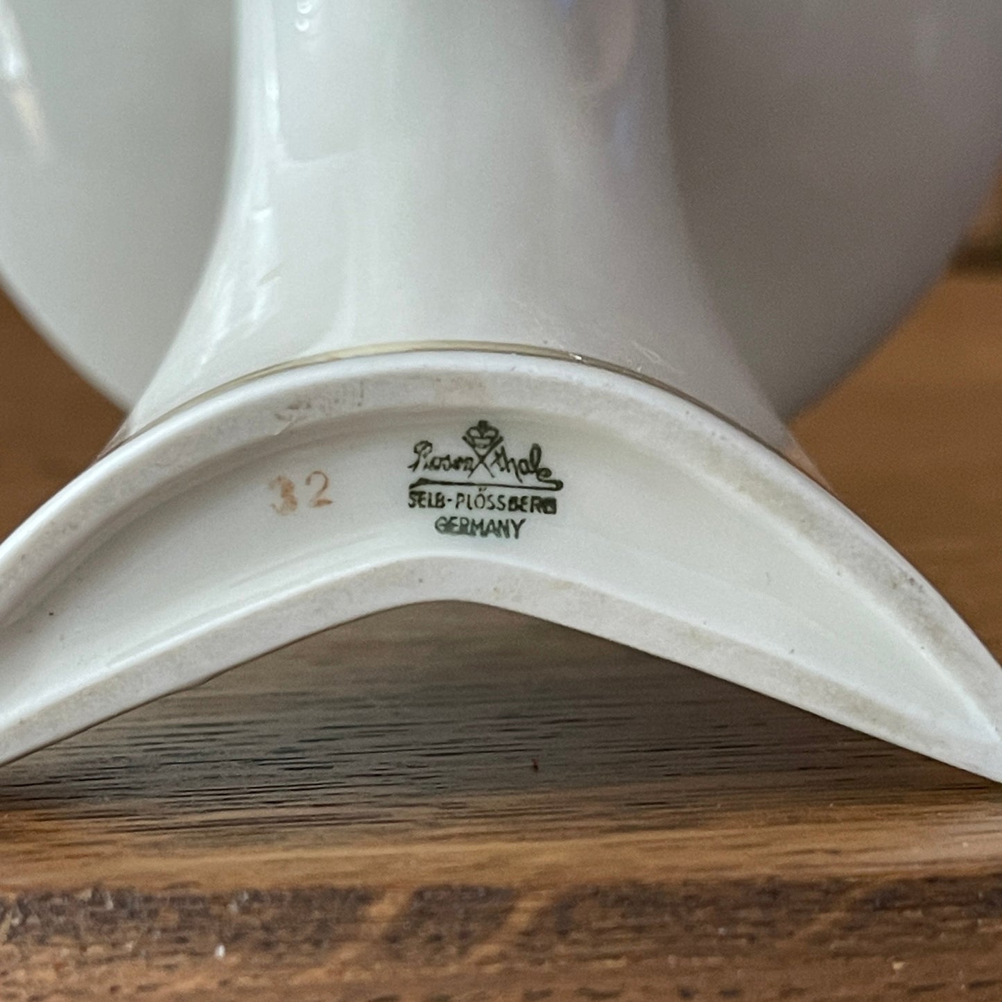 Close-up of a white ceramic product with a brand logo on a wooden surface