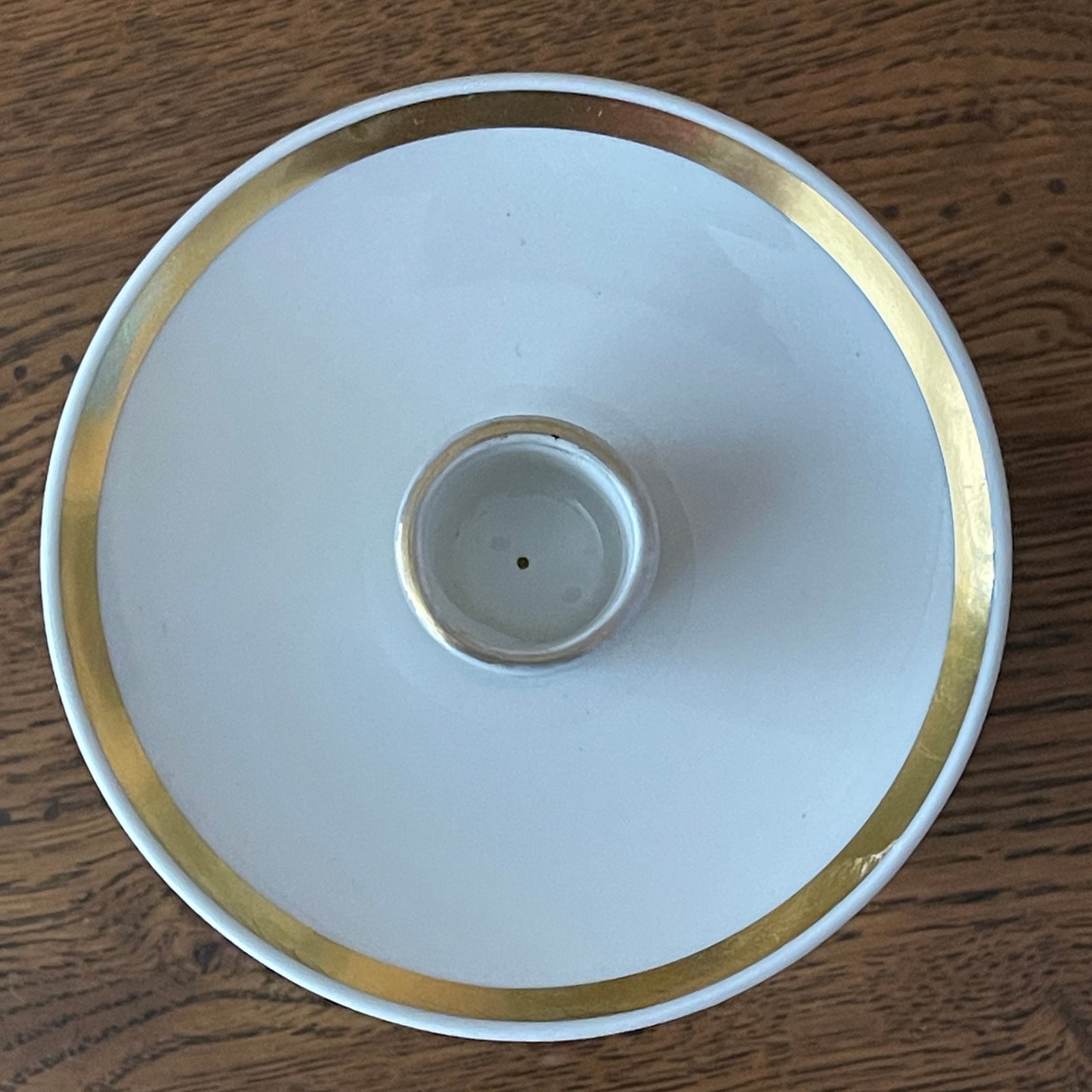 White candle holder with gold rim on a wooden surface