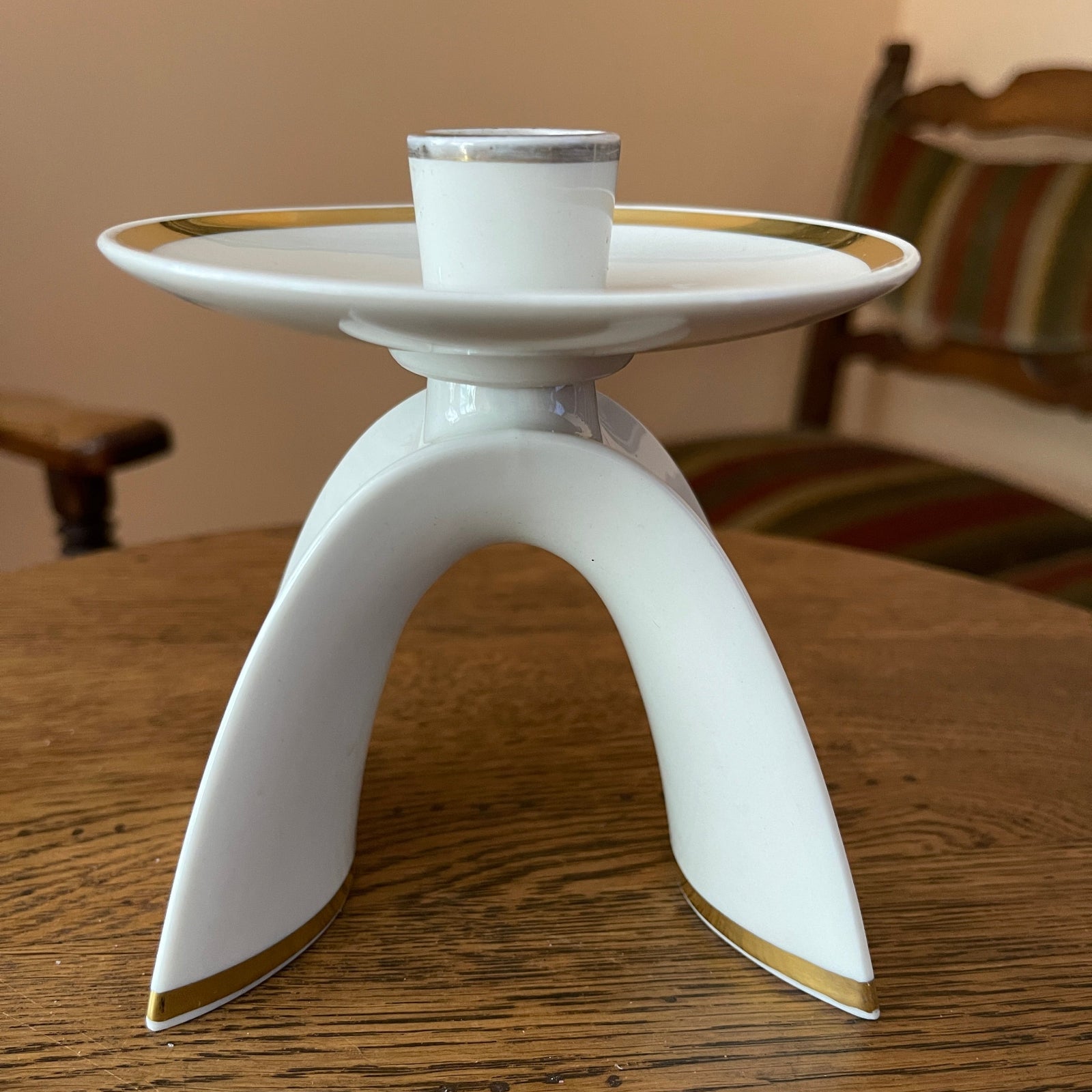 White candle holder with gold accents on a wooden table