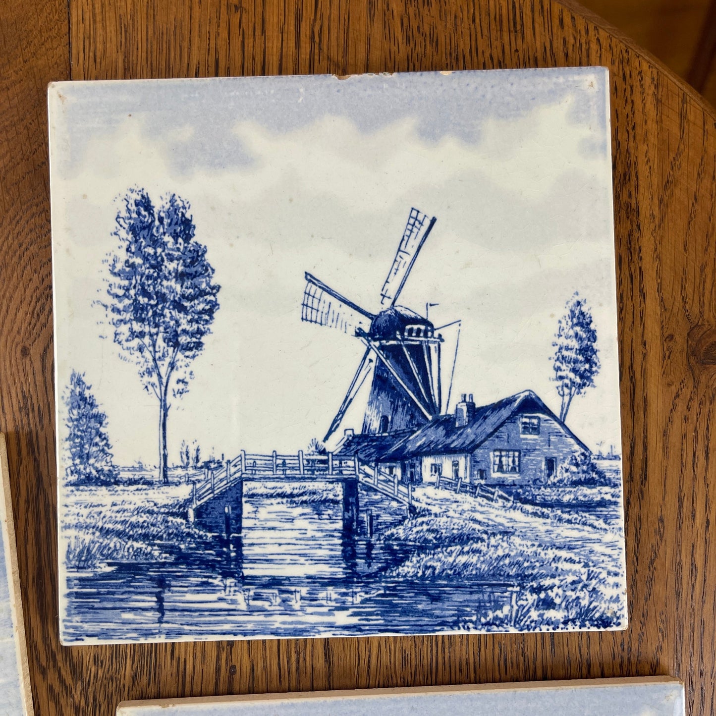 Decorative tile with a blue and white windmill design on a wooden surface